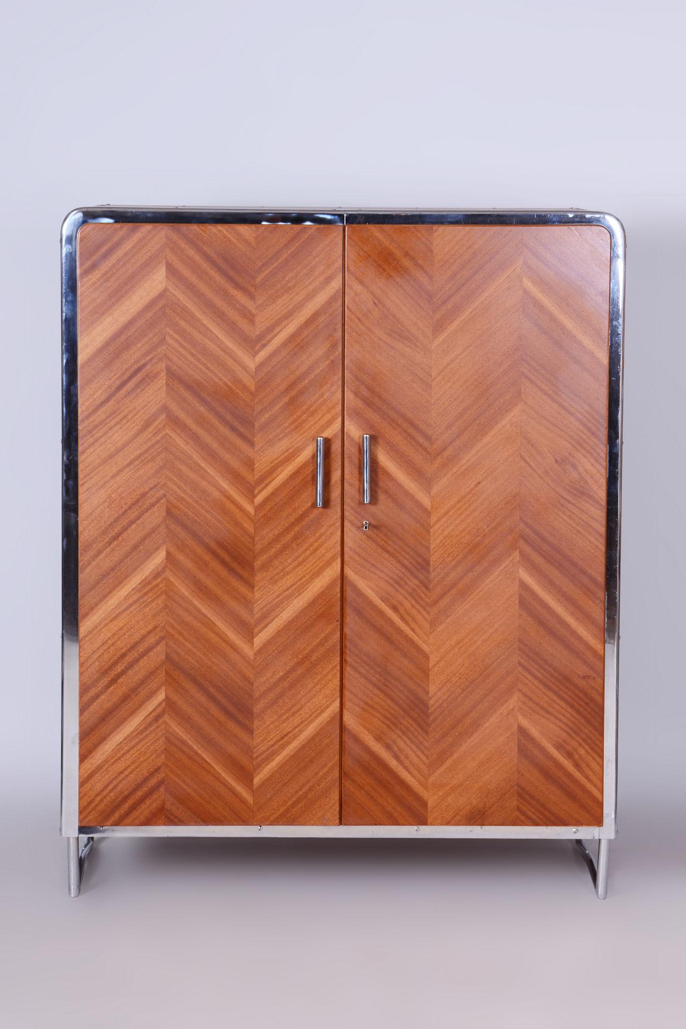 Made by Slezak Factories, a unique Czech furniture brand specialising on chrome and bent metal furniture

The mahogany veneer on the door is folded into a tree pattern.

The cabinet was manufactured by Slezák factories under license from Thonet.

It
