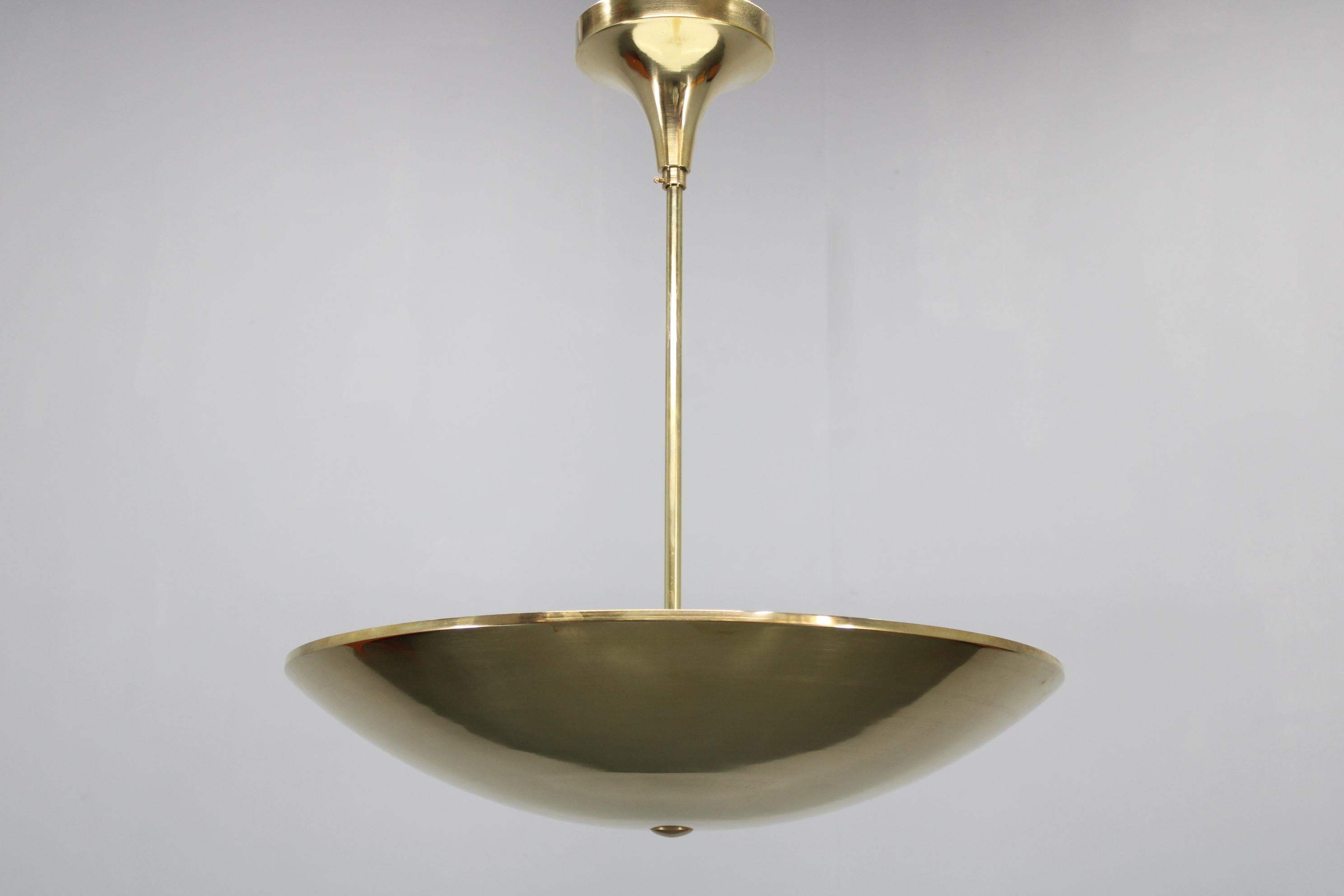 This elegant chandelier captures the essence of Bauhaus and Art Deco design from 1930s Czechoslovakia. Expertly crafted from brass-plated iron sheet, the fixture showcases clean lines and a refined, minimalist bowl shade, making it a timeless