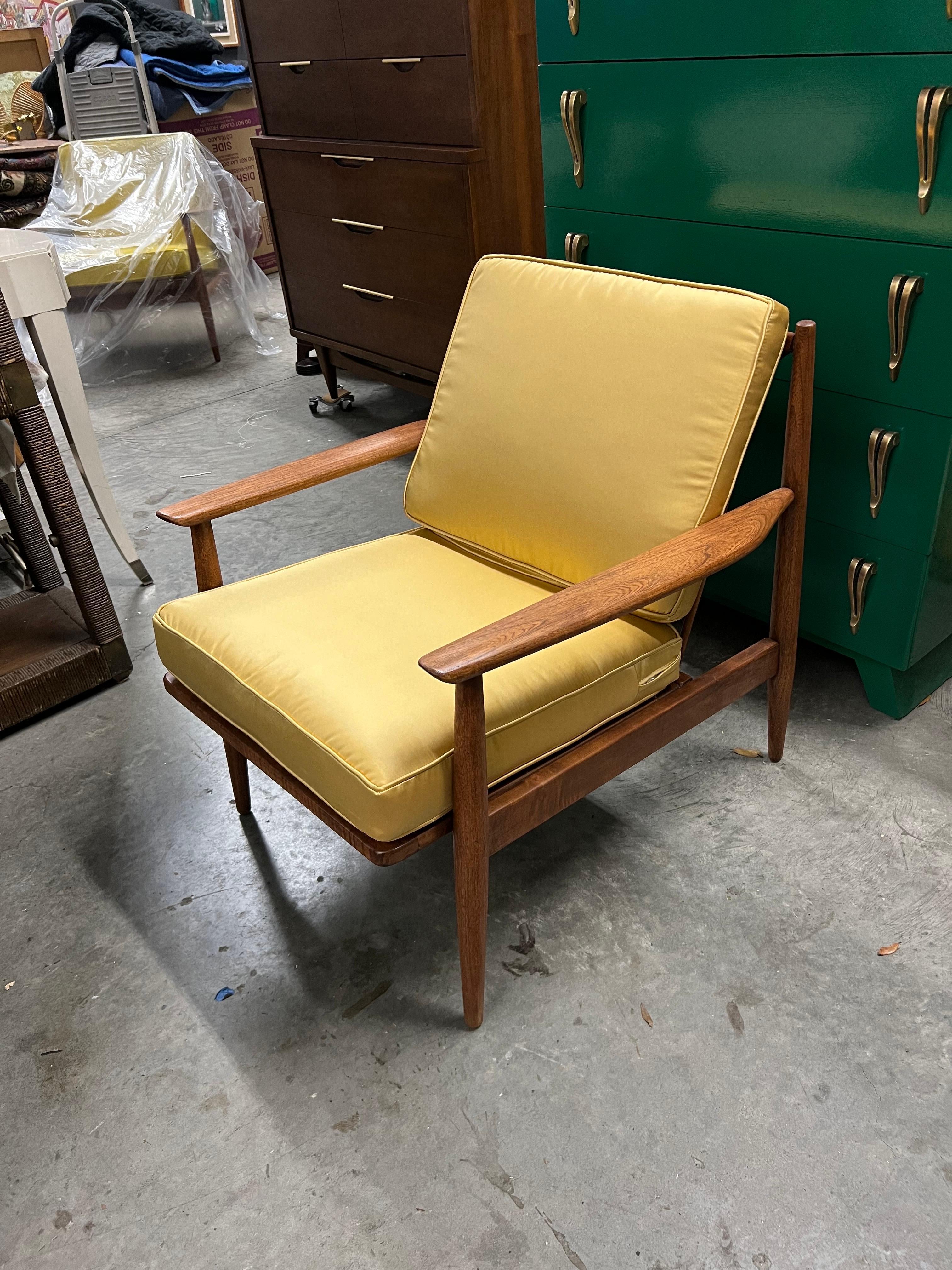Fauteuil classique de style moderne du milieu du siècle dans une finition en noyer qui constitue une incroyable pièce d'accent dans le salon. De superbes lignes avec un cadre en fuseau et des accoudoirs sculptés donnent une touche délicate qui