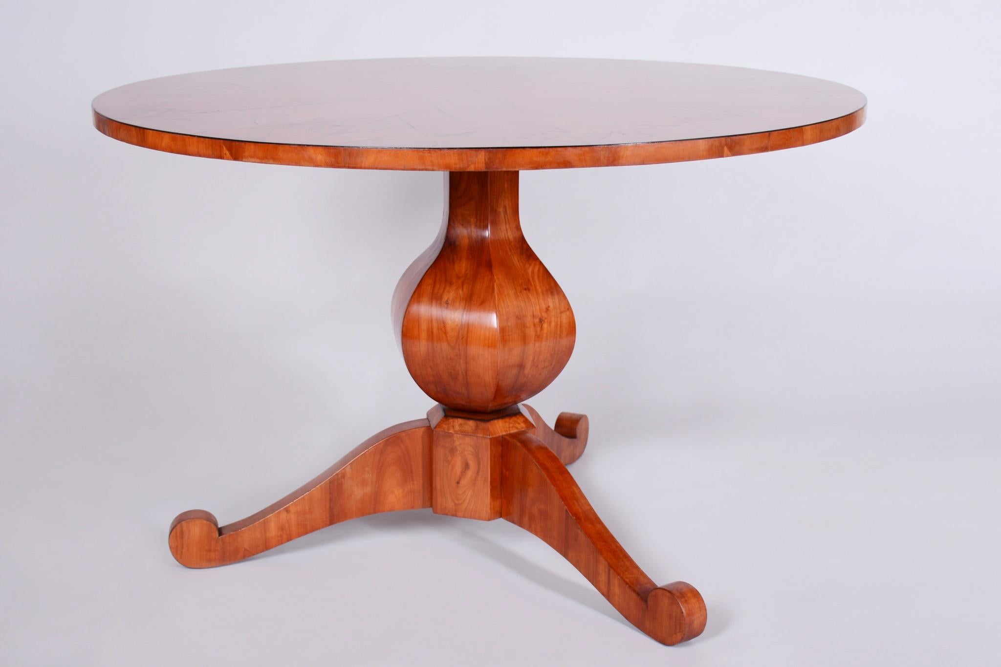 This elegant round Biedermeier dining table comes from Austria from the first half of the 19th century. It is made of spruce blockboard with cherry veneer and has undergone careful restoration. During the restoration, the original polish was