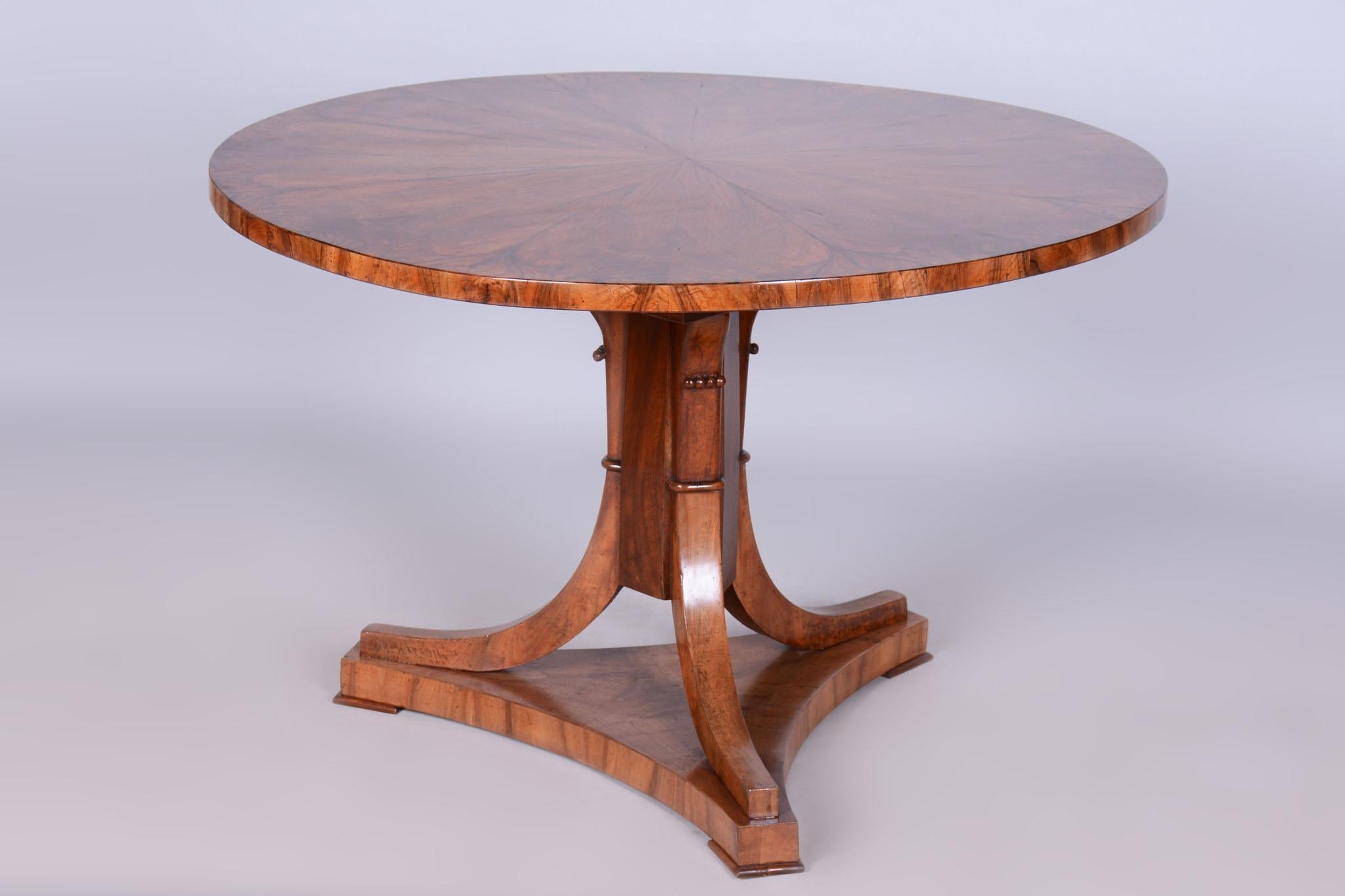 This elegant round dining table, originating from Austria in the early 19th century, is a fine example of the Biedermeier style. Made of solid spruce with walnut veneer, it impresses with its authentic appearance and precise craftsmanship. The