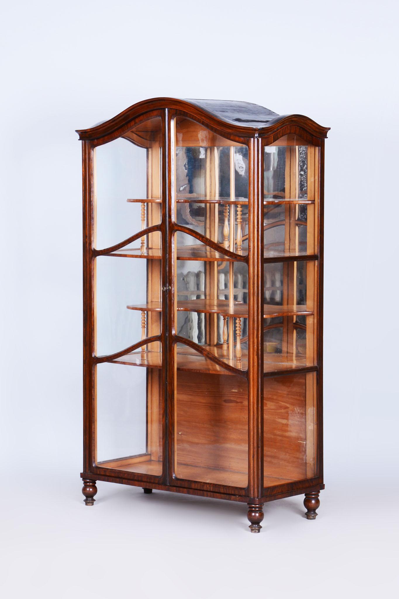 This elegant Biedermeier display cabinet comes from Bohemia from the mid-19th century. It is made of a combination of walnut and maple wood and has undergone careful restoration. During the restoration, the original polish was revived. The display