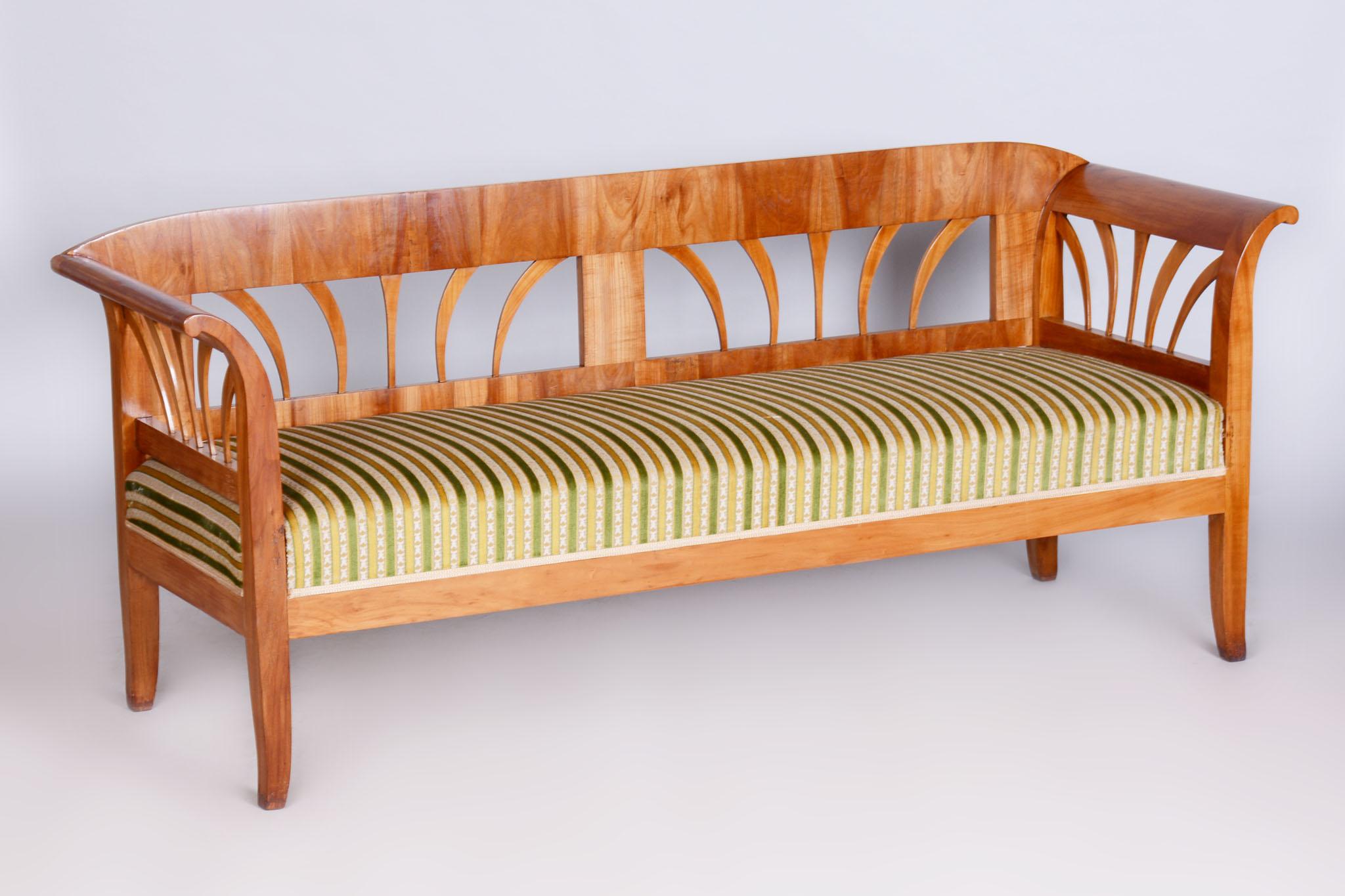 Dieses Biedermeier-Sofa stammt aus dem frühen 19. Jahrhundert und ist in Österreich entstanden. Er ist aus massivem Kirschbaumholz gefertigt, das mit Fichtenholz furniert ist, was ihm Stärke und ein charakteristisches Aussehen verleiht. Das Sofa