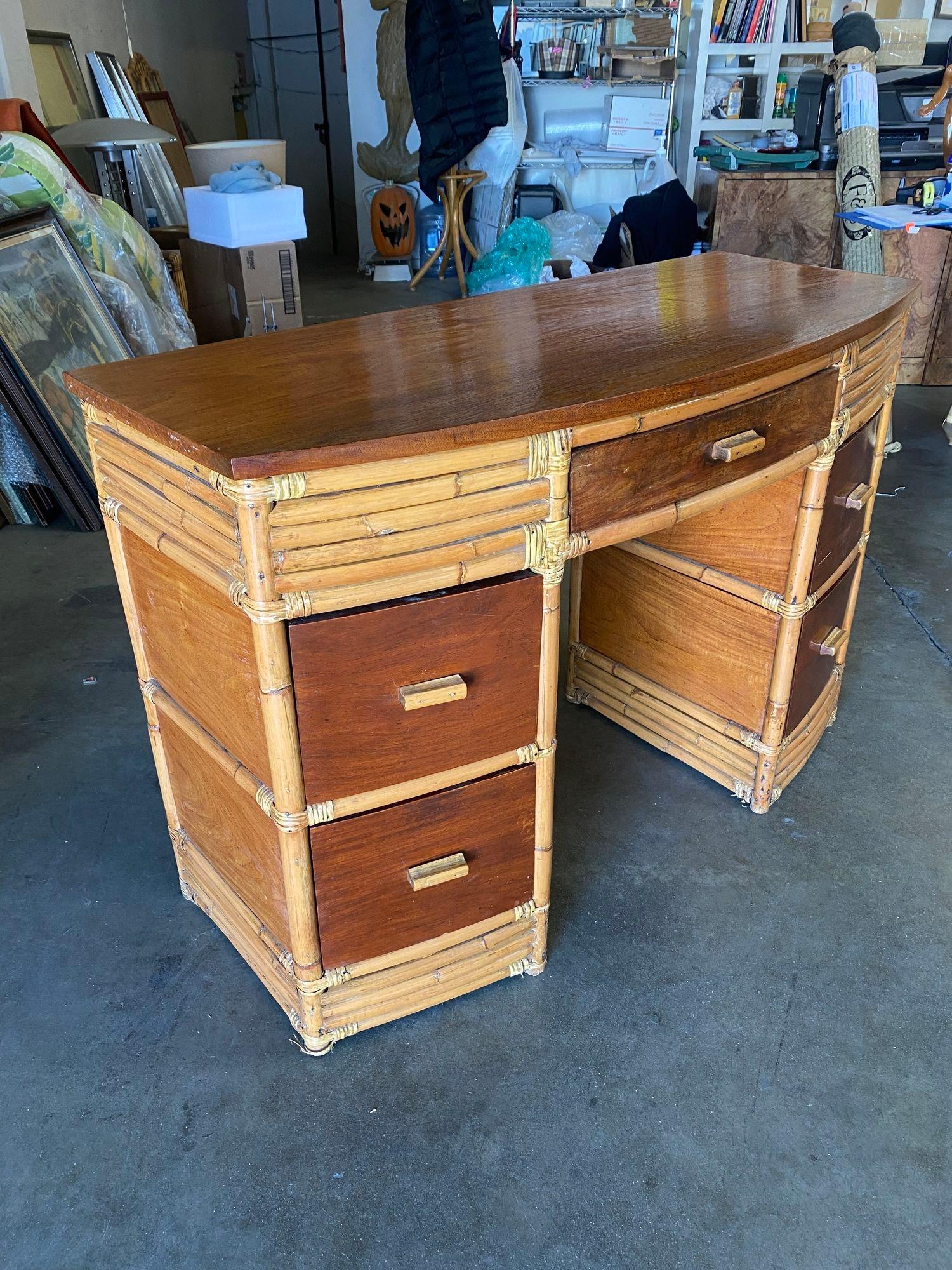 Restored very large stacked rattan desk, with Filipino mahogany Drawer fronts, side panels, and top. The desk features a center drawer and 4 side drawers. Beautiful stacked rattan legs race from the top to the bottom, creating a great modern look.