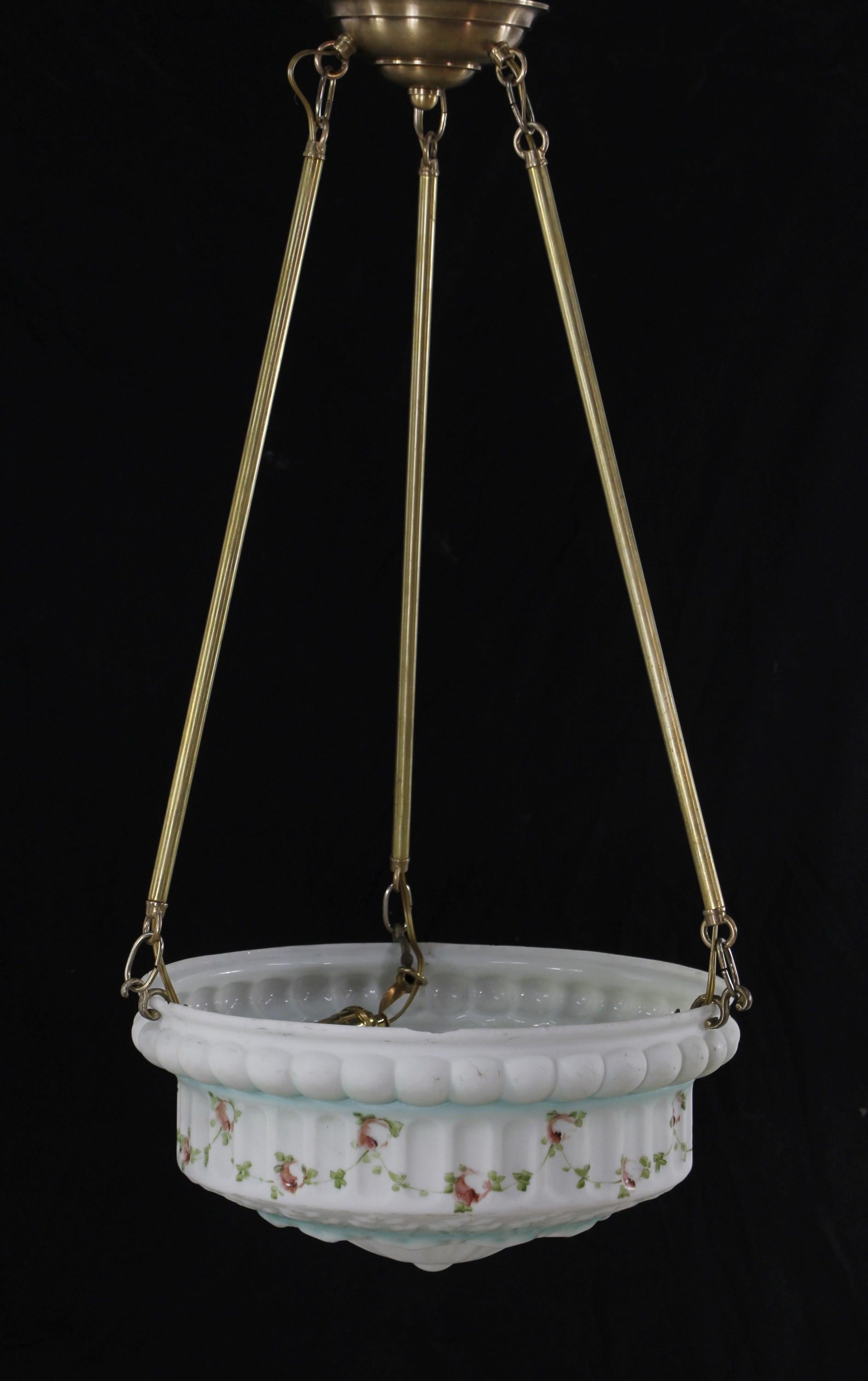 Suspension de plat antique en verre moulé blanc avec des détails floraux peints en rose et des détails de feuillage vert avec des éclaboussures de bleu. Cette lampe est suspendue à trois poteaux en laiton avec un baldaquin en laiton. Nettoyé et