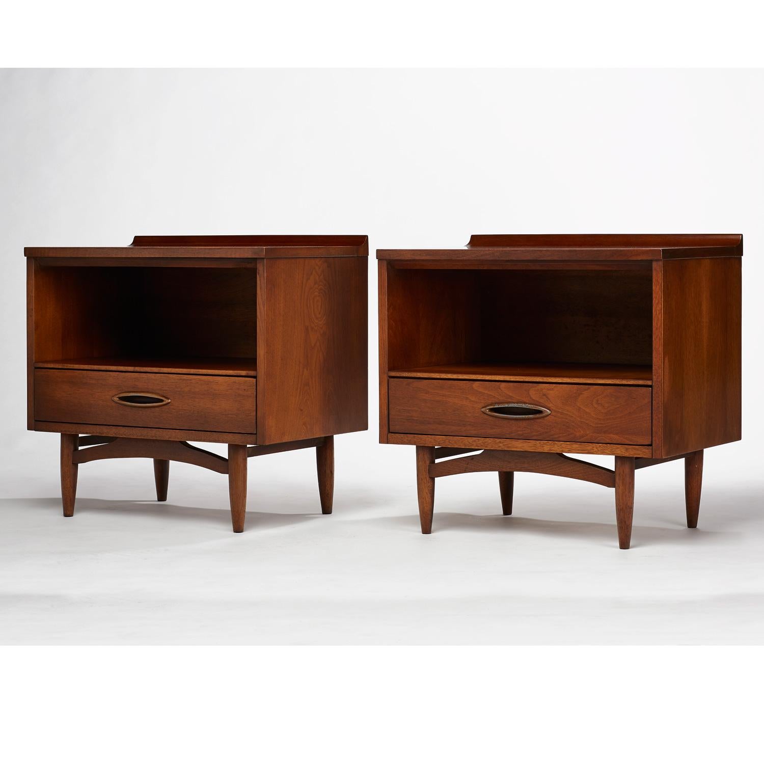 Mid-Century Modern sculptra nightstands by Broyhill Premier. Back edge of top surface is accented with an upward reaching sculpted lip. Open cabinet storage with one pull-out drawer on metal glides. Inset elliptical handles on the drawers enhance