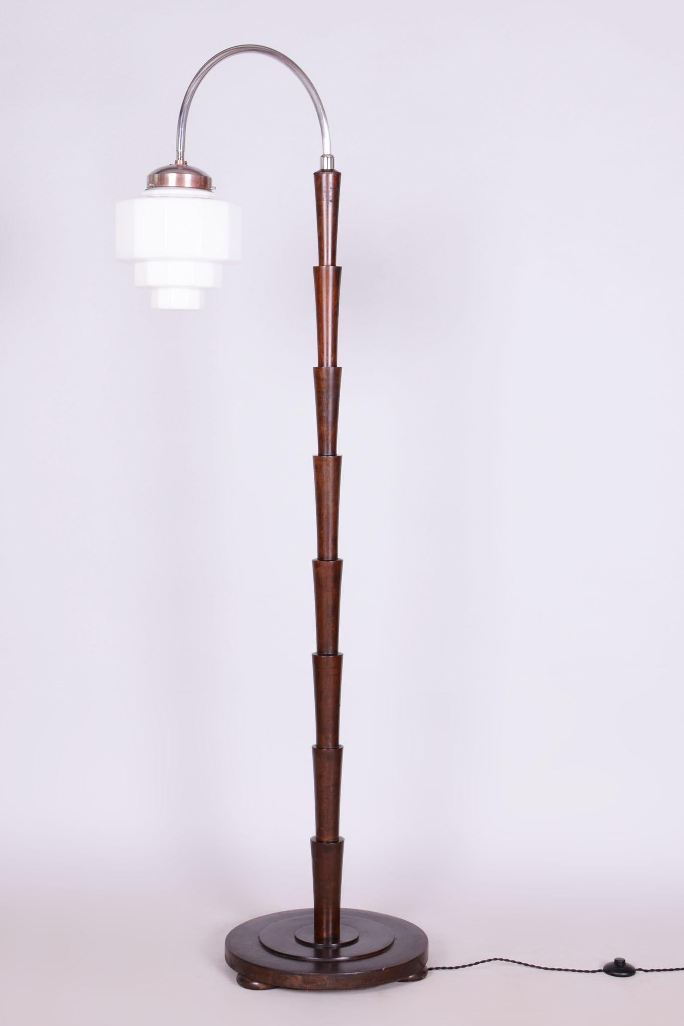 This floor lamp in Cubist style from the Art Deco period originates from Czechoslovakia in the early 20th century. It is made of beech and has been completely restored.

The lamp features the original well-preserved shade made of milk opal glass,