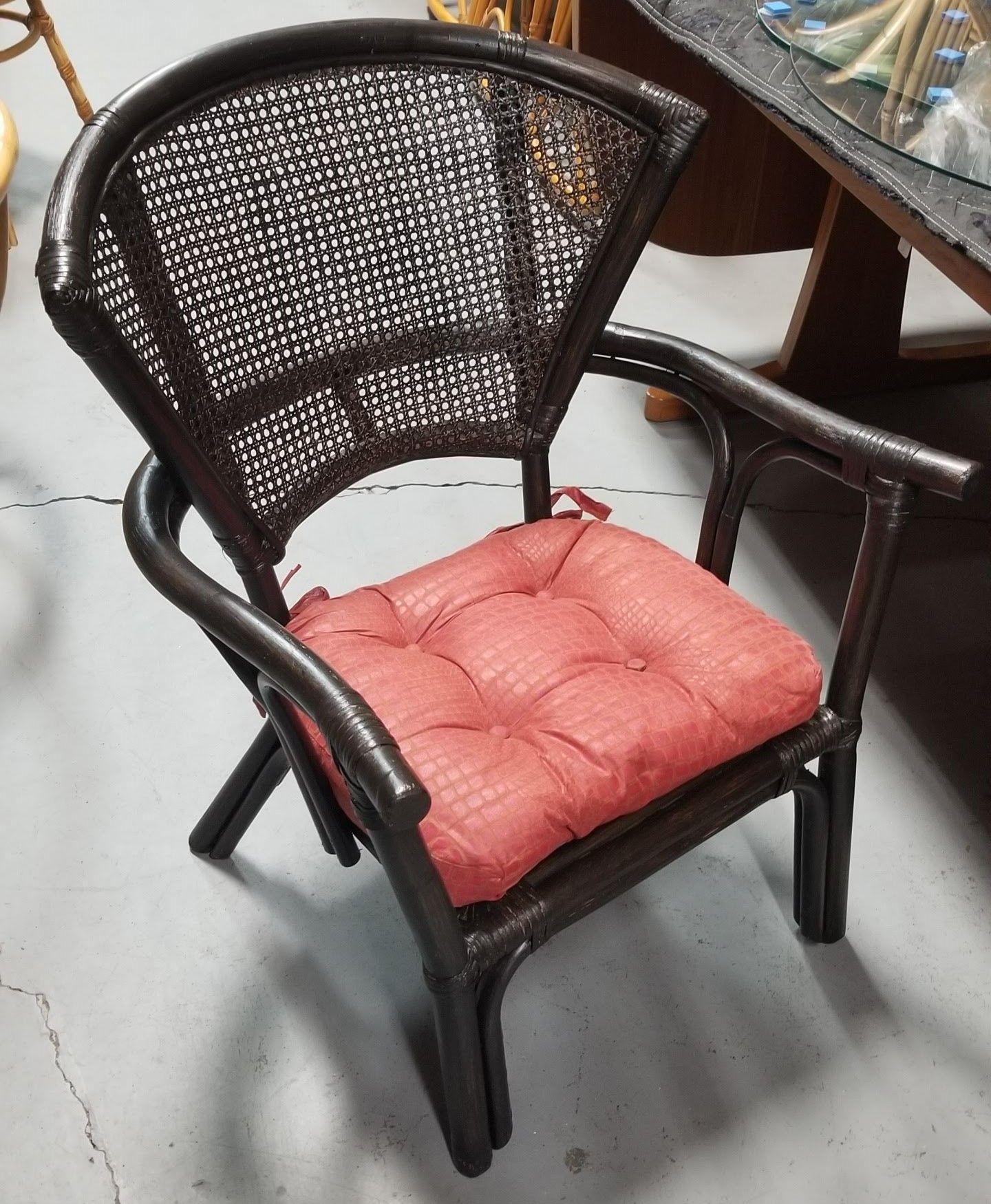 Immerse yourself in the charm of a meticulously restored vintage rattan armchair. The deep, lustrous dark stain enhances its allure, while the intricate cane weave fan back and gracefully arched arms provide comfort and style, making it a