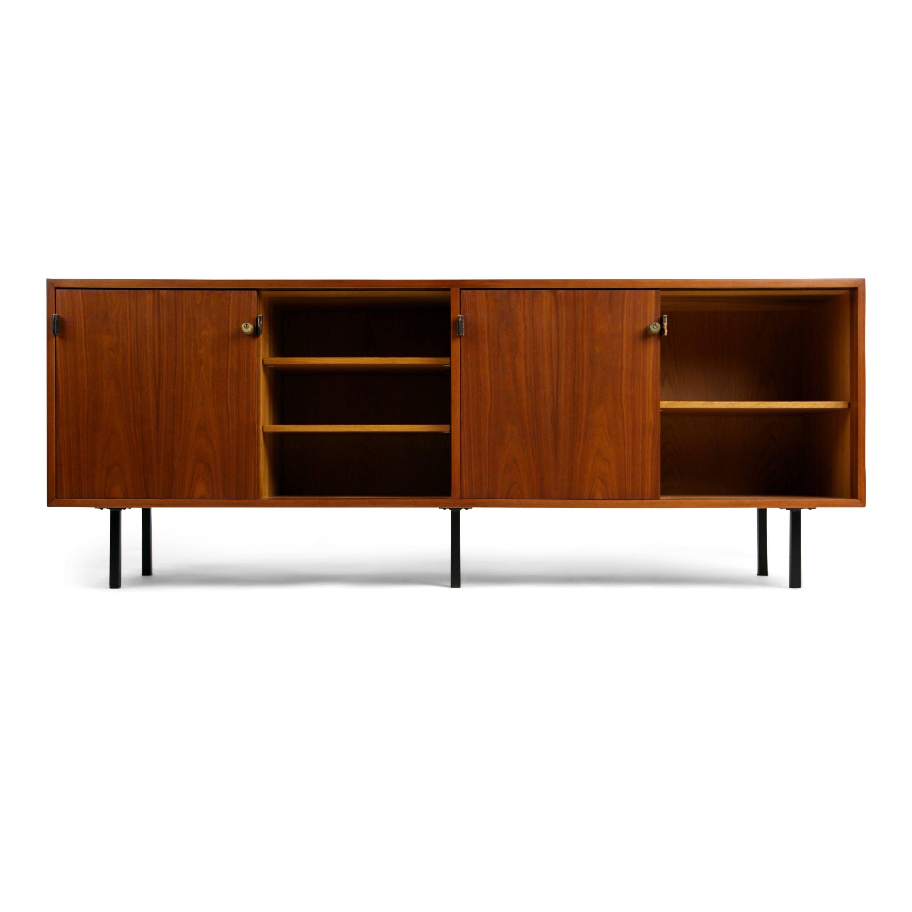 Sleekly designed credenza by Florence Knoll for Knoll Associates. This newly restored sideboard is fabricated from walnut and features the original leather pulls, hardware, and locks which have been fitted with new keys. The interior comprises of