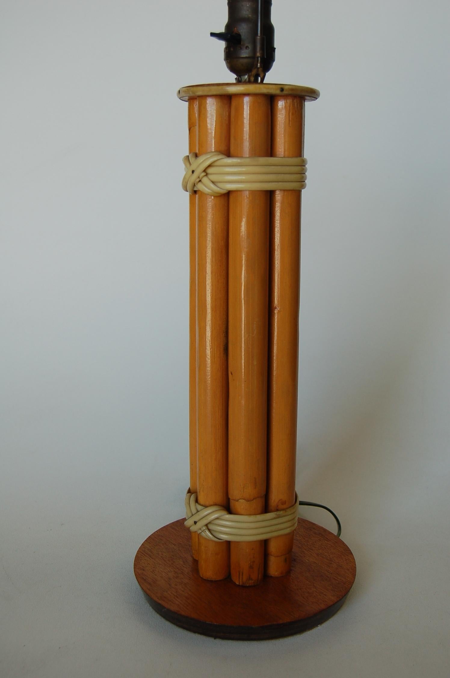 Restored midcentury round rattan table lamp featuring seven decorative rattan poles centered around a rattan post all fixed to a wood circular base, circa 1950. 

Measures: 7