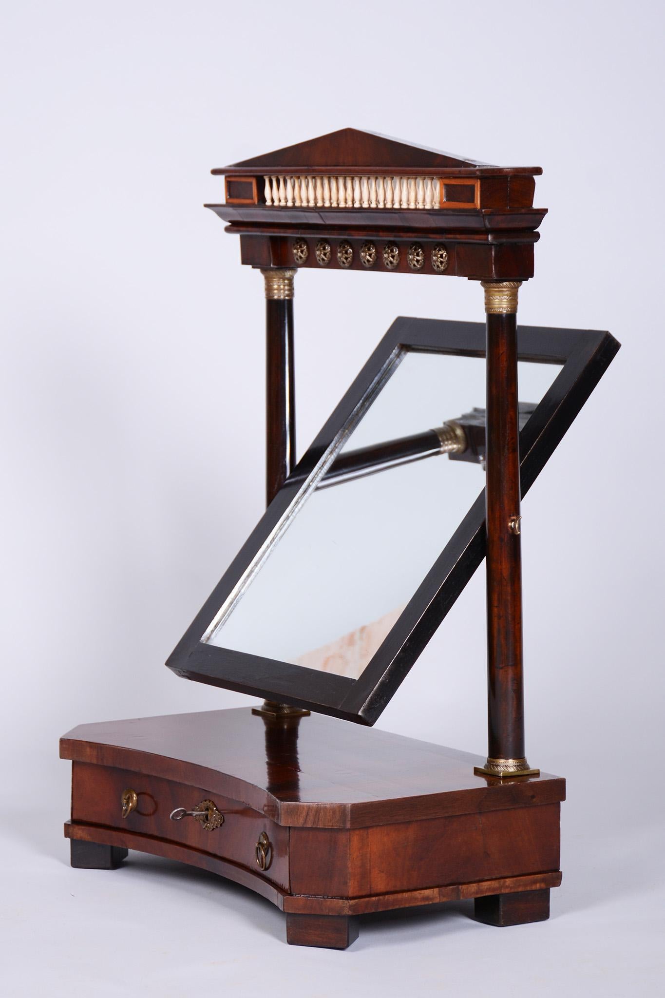 Este elegante espejo vestidor (espejo de mesa) de estilo Imperio procede de Francia, de finales de los siglos XVIII y XIX. Está hecha de madera maciza de roble chapada en caoba y adornada con herrajes de latón y columnas decorativas de hueso.

El