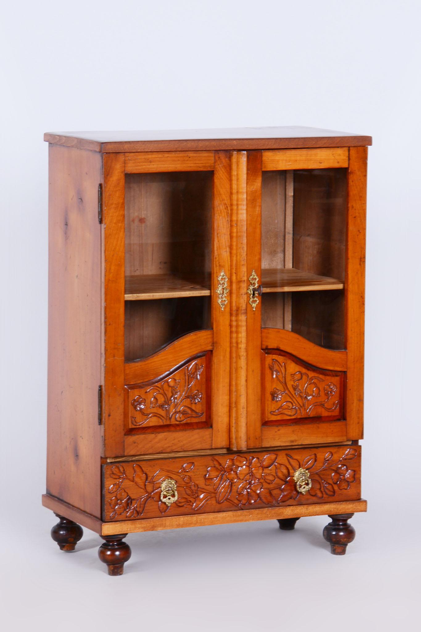 Cette armoire à deux portes de la seconde moitié du XIXe siècle provient de la République tchèque et est fabriquée à partir d'une combinaison de bois de cerisier et d'épicéa. Son design ressemble à une bibliothèque miniature, ce qui ajoute à son