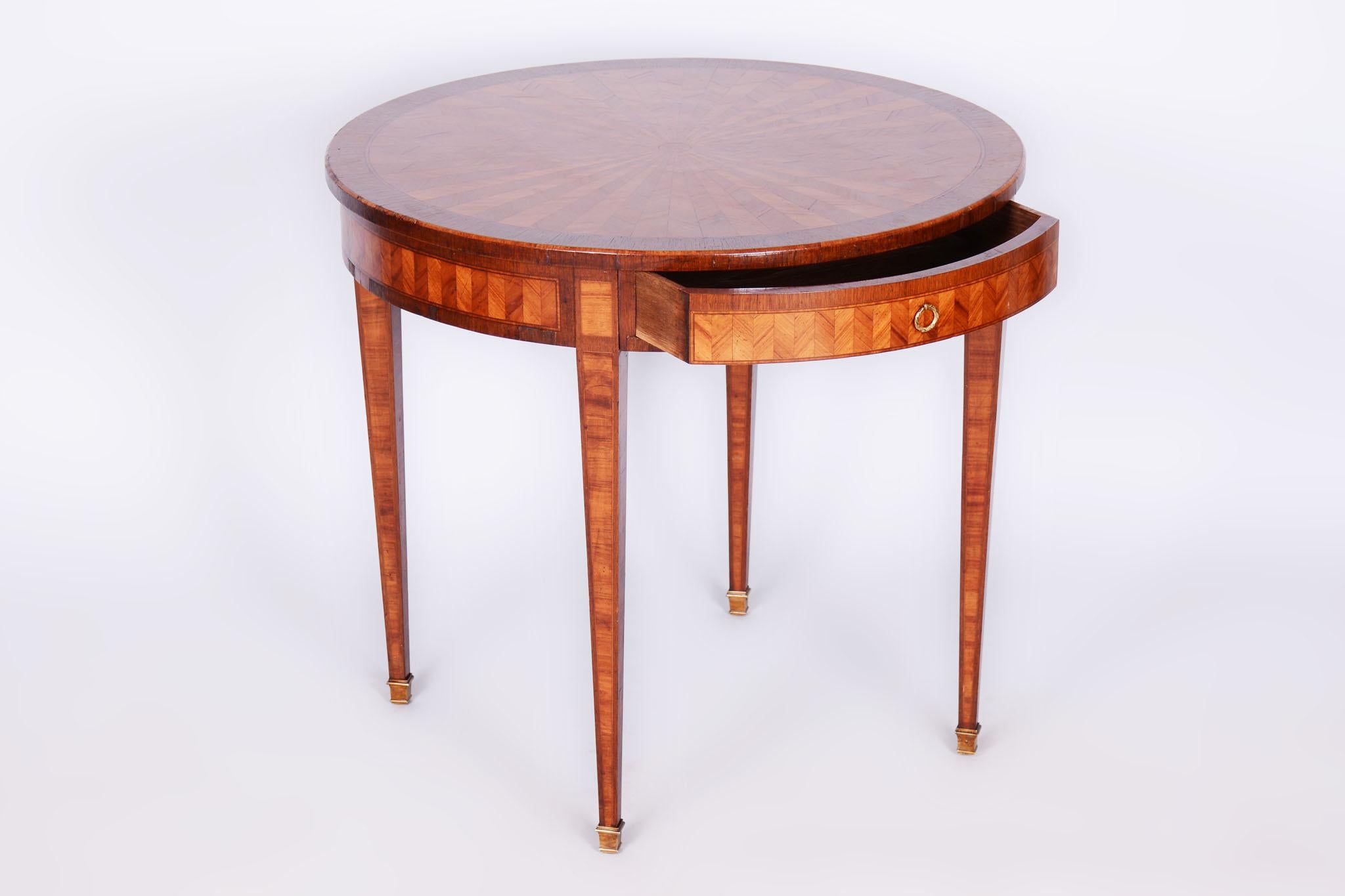 Questo elegante tavolo rotondo classicista proviene dalla Francia e risale alla metà del XIX secolo. È realizzato con una combinazione di impiallacciatura di ciliegio e mogano con intarsio e dispone di accessori in ottone. Il tavolo è stato