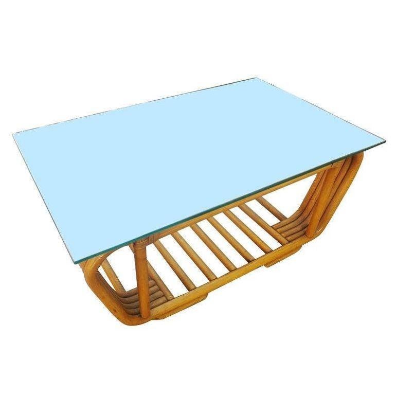 Beautifully restored Frankl style rattan five-pole rattan coffee table has an unusual bent rattan round base, blending style and vintage charm with modern comfort. The five rattan poles are stacked together in a double C shape. The glass top rests