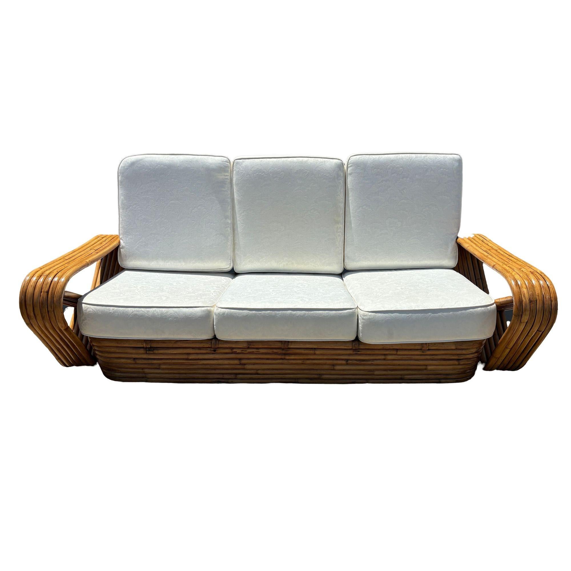Il divano a sei posti in rattan di metà secolo presenta braccioli quadrati a forma di pretzel e una classica base impilata. Realizzato con pali di rattan piegati a vapore, il divano presenta un involucro decorativo in vimini intrecciato con strisce