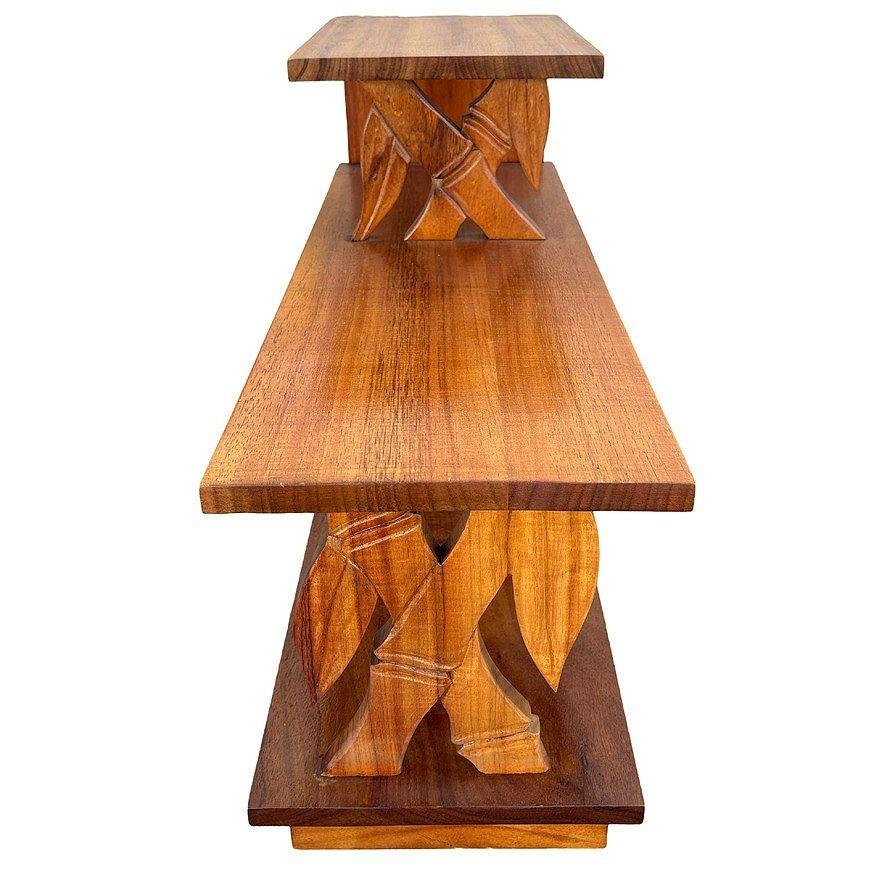 Cette table d'appoint à trois niveaux, magnifiquement restaurée, est fabriquée en bois de koa sculpté à la main. Les deux panneaux avant sont sculptés en forme de tiges de bambou avec des feuilles. Le bois de Koa est connu pour son grain distinctif