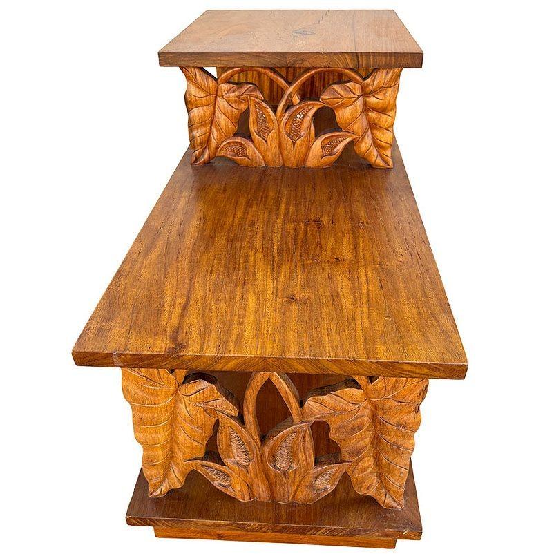This beautifully restored 3-tiered side table is crafted from hand-carved koa wood featuring 2 front panels sculpted into the shape of Anthurium Floral. Koa wood is known for its distinctive grain and rich natural tones. The three-tiered structure