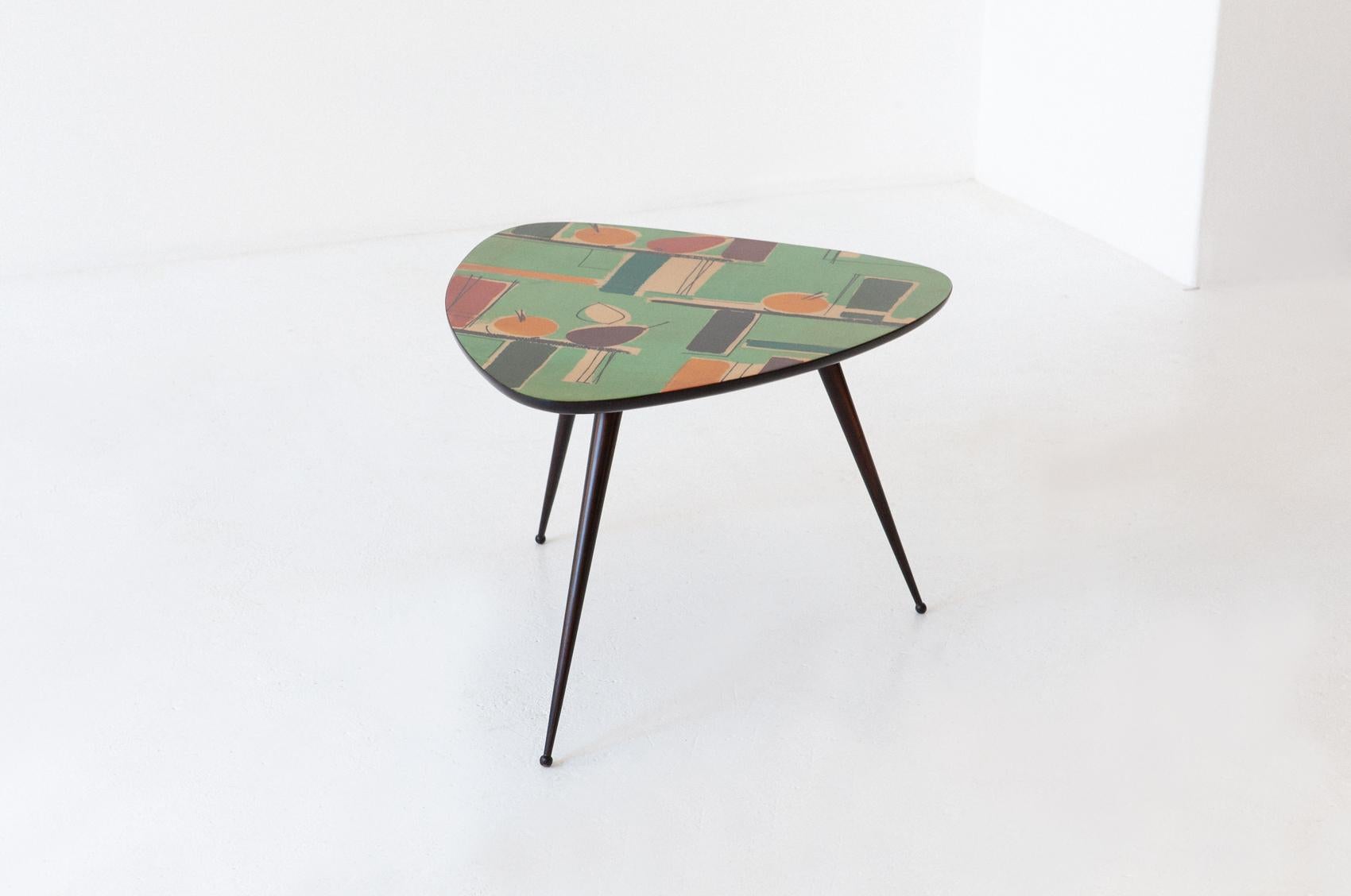 A trioval low table manufactured in Italy during the 1950s. COD. T80
The triangular top has been painted by hand, drawings represent pears and apples. Bright colors on green and brown shades.
The brown legs have been restored, polished by hand