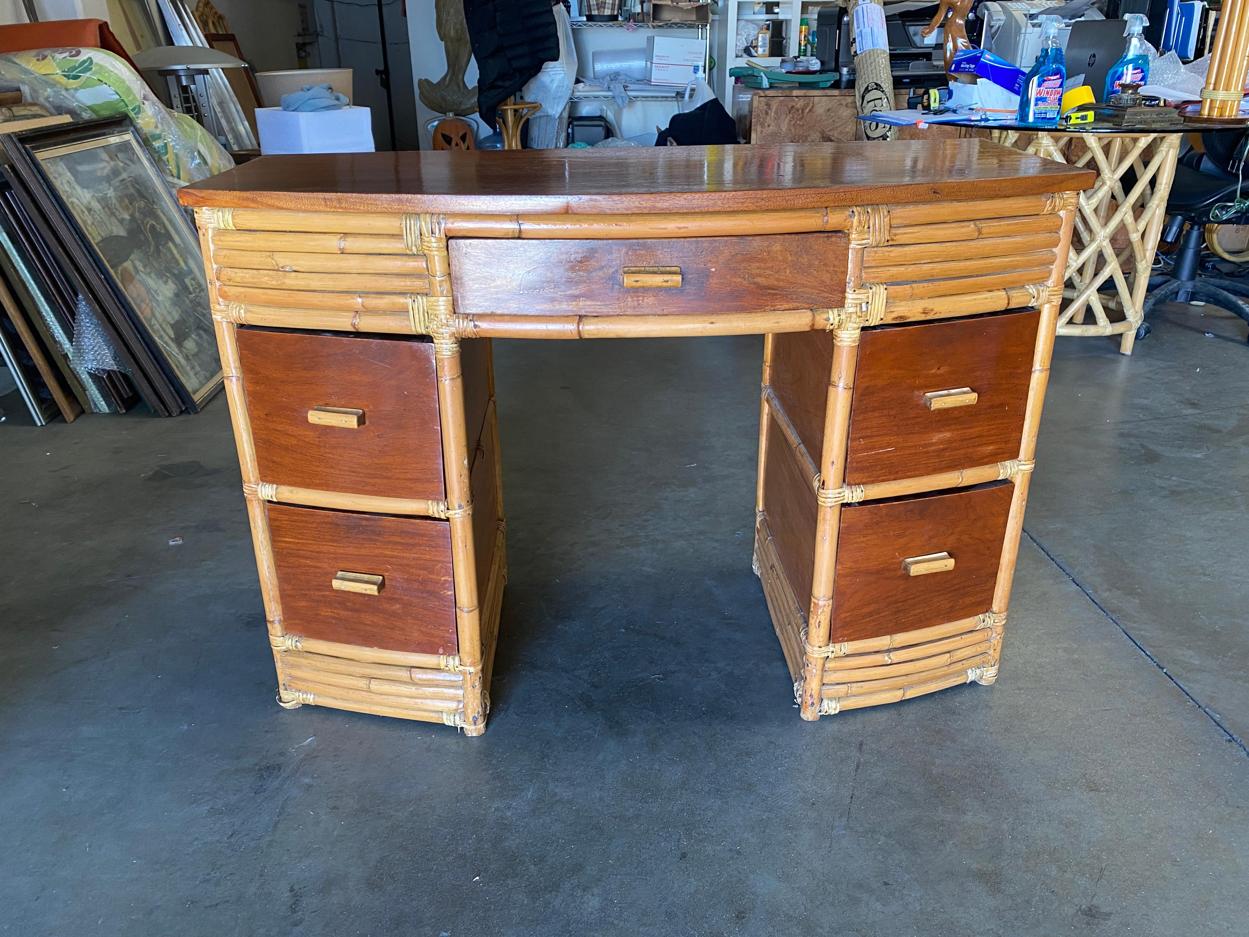 Restored very large stacked rattan desk, with Filipino mahogany Drawer fronts, side panels, and top. The desk features a center drawer and 4 side drawers. Beautiful stacked rattan legs race from the top to the bottom, creating a great modern look.