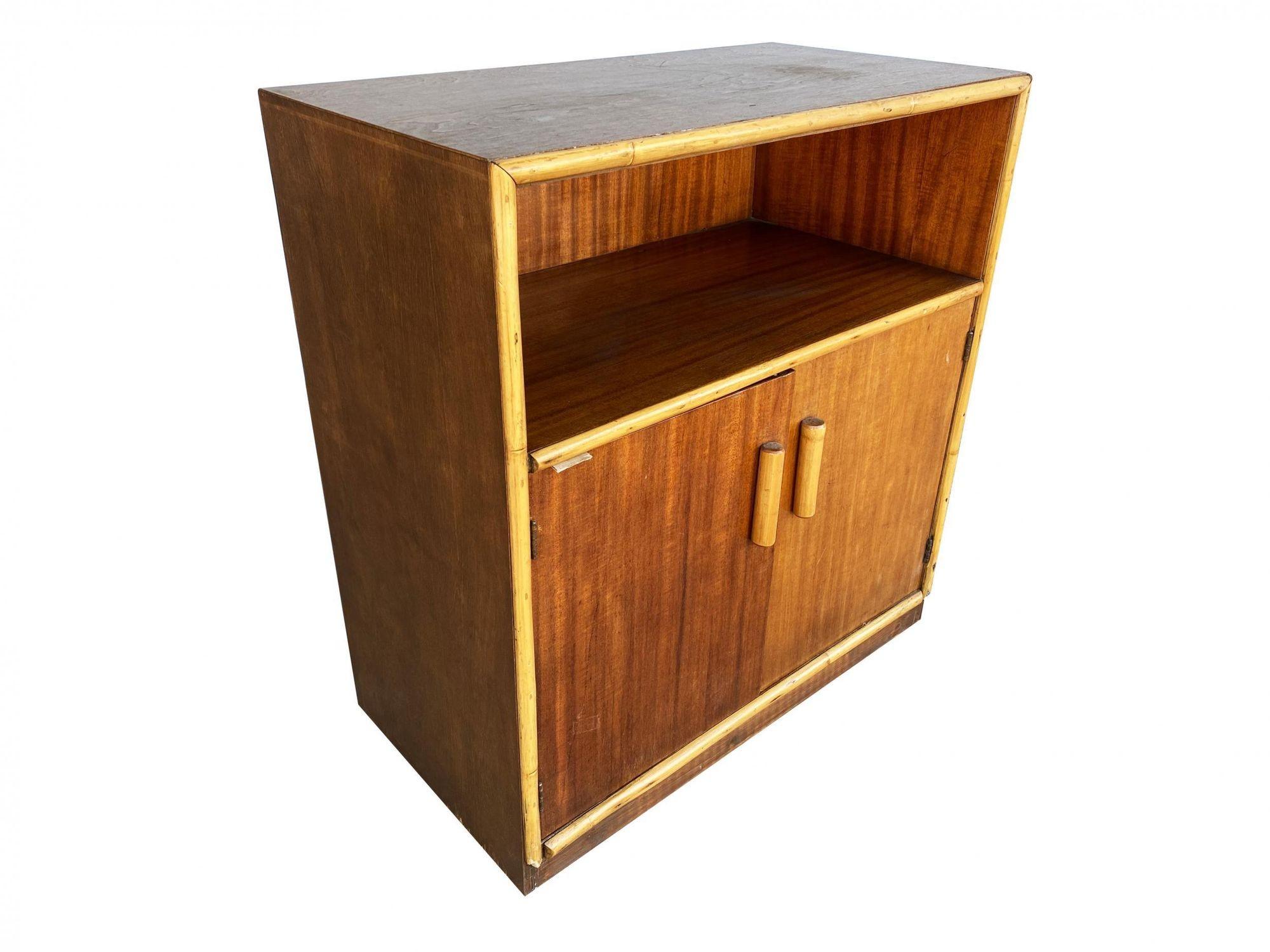 Restored Post War Mahogany Cabinet with Rattan Accents featuring a rattan trim with single shelf cubby space and a 2-door cabinet underneath which opens to two fixed shelves.

1940, United States


We only purchase and sell the best and finest