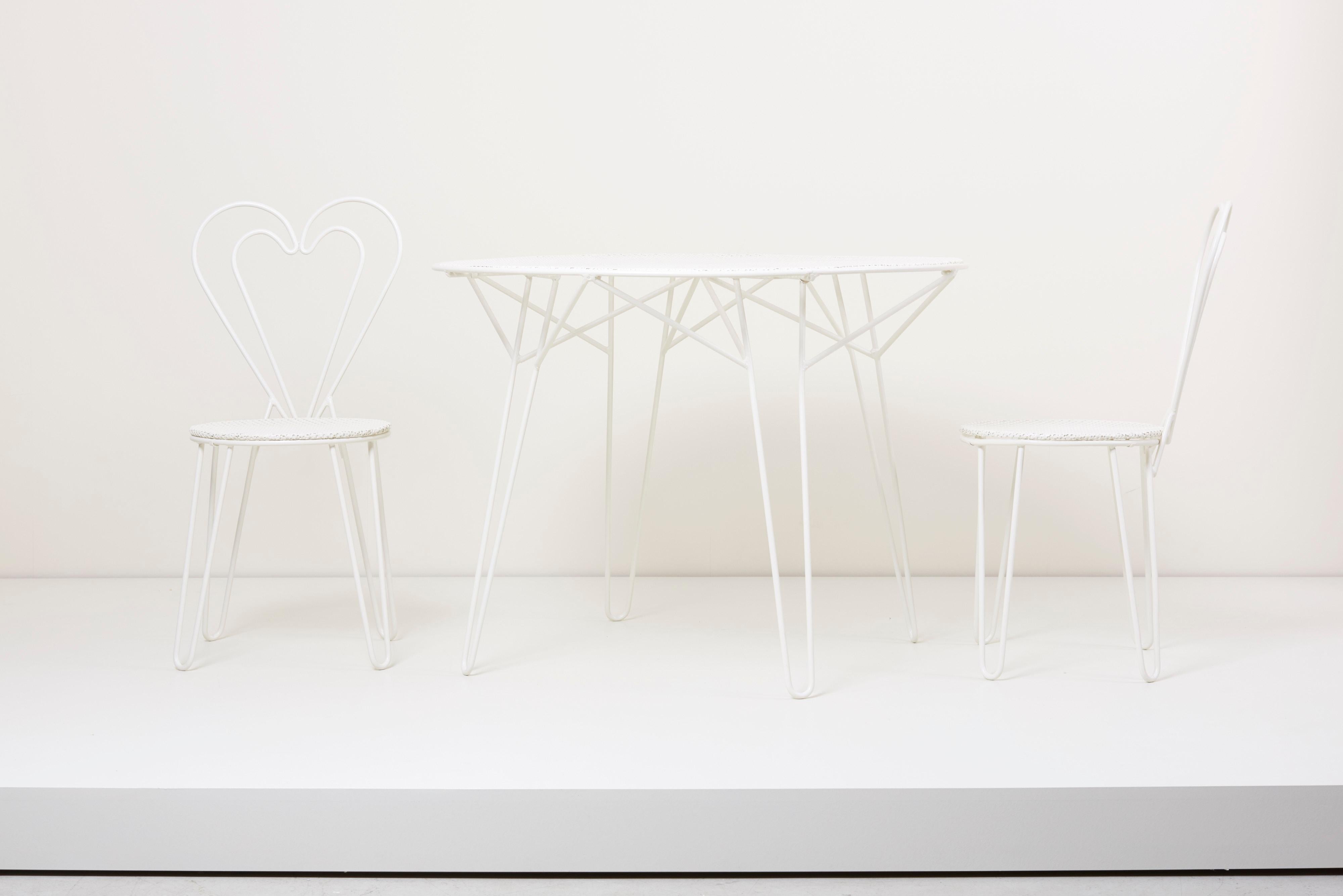 Cet ensemble comprend une table d'extérieur Classic Mategot et deux chaises d'appoint en forme de cœur de Mathieu Mategot. L'ensemble est restauré (non rouillé et recouvert d'une couche d'apprêt en bonne et due forme), qu'il soit parfait pour une