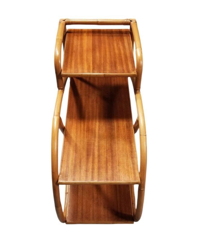 This beautifully restored Paul Frankl-inspired rattan side table features 3-tier table tops with 1 strand 3/4 pretzel rattan sides and red stained mahogany table tops. This Frankl style side table is a perfect fit alongside your bed or sofa. Both