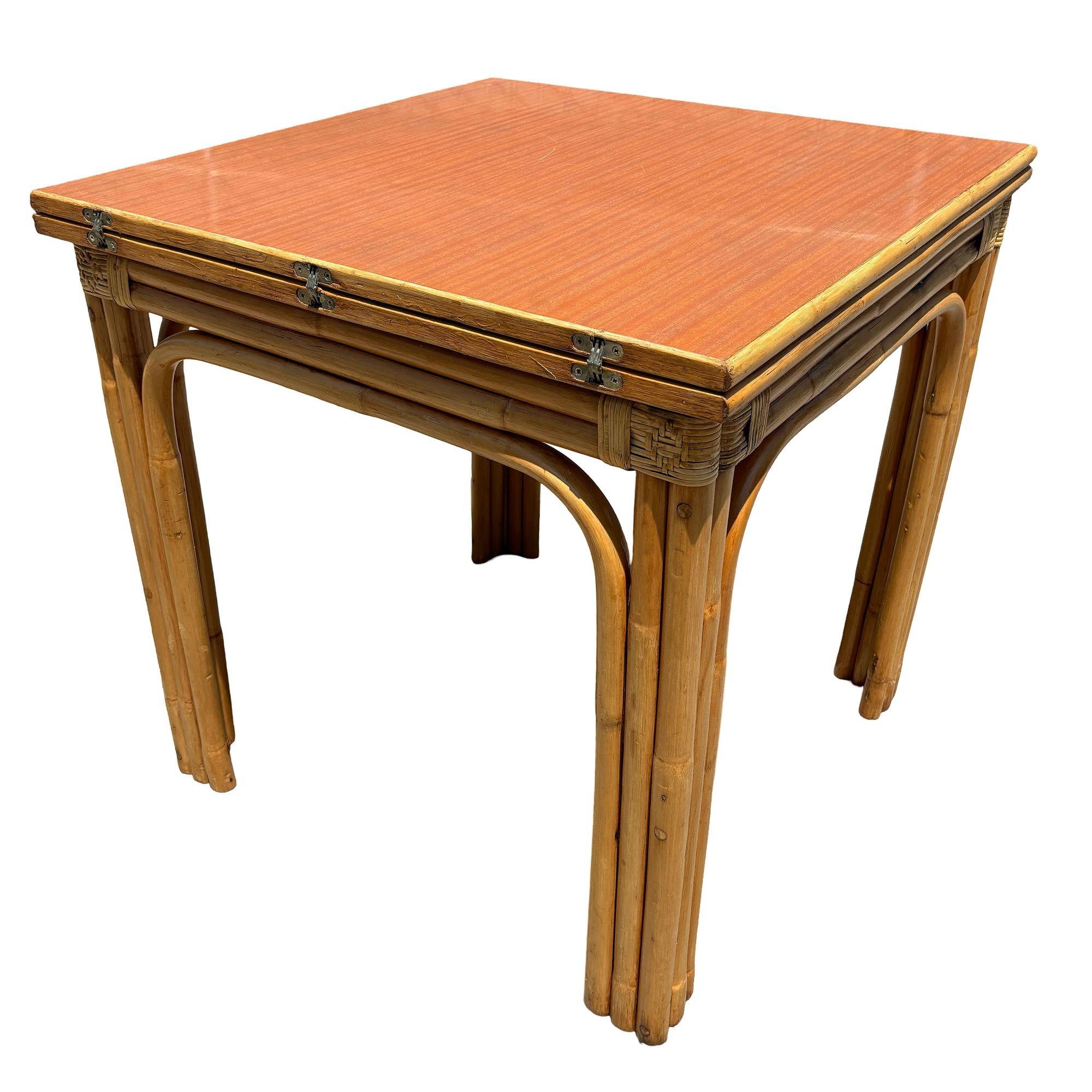 This beautifully restored Paul Frankl-inspired Mid-century rattan and wood grain Formica dining table. The table includes an expanding 2-piece hinge leaf top, allowing for easy expansion to accommodate more guests. The rattan base offers a natural,