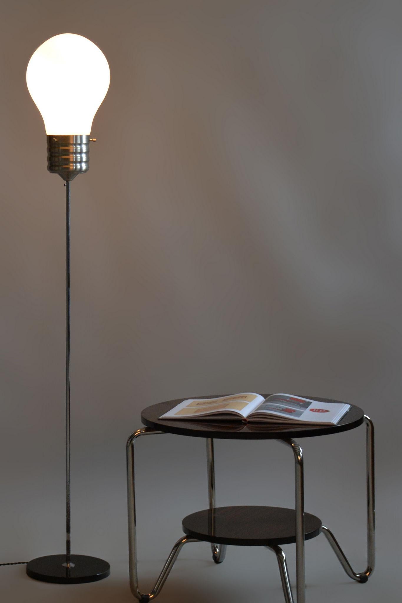 Questa elegante lampada da terra degli anni '60 è un esempio iconico del design del Mid-Century originario della Germania. La combinazione di cromo e acciaio annerito conferisce alla lampada un aspetto sofisticato, mentre il paralume in vetro