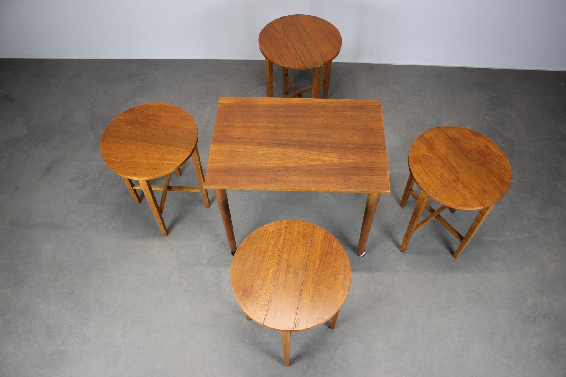Elegant and functional Mid-Century Danish design by Poul Hundevad, this 1960s folding table with four stools is both practical and sculptural. Each stool folds flat and stores seamlessly inside the table frame, creating a compact, mobile unit ideal