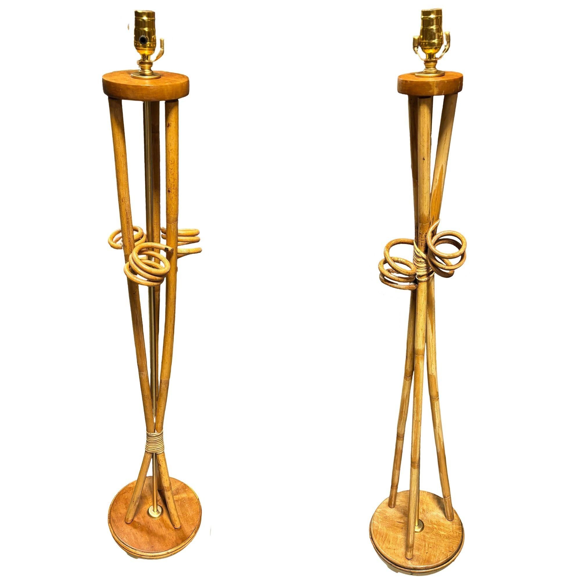 These beautifully restored Paul Frankl-inspired Rattan lamps feature a pair of Floor Lamps and with Matching Tabletop Lamp. Each lamp features an elegant hourglass silhouette with bent rattan poles fixed to Mahogany caps. All lamps include brass