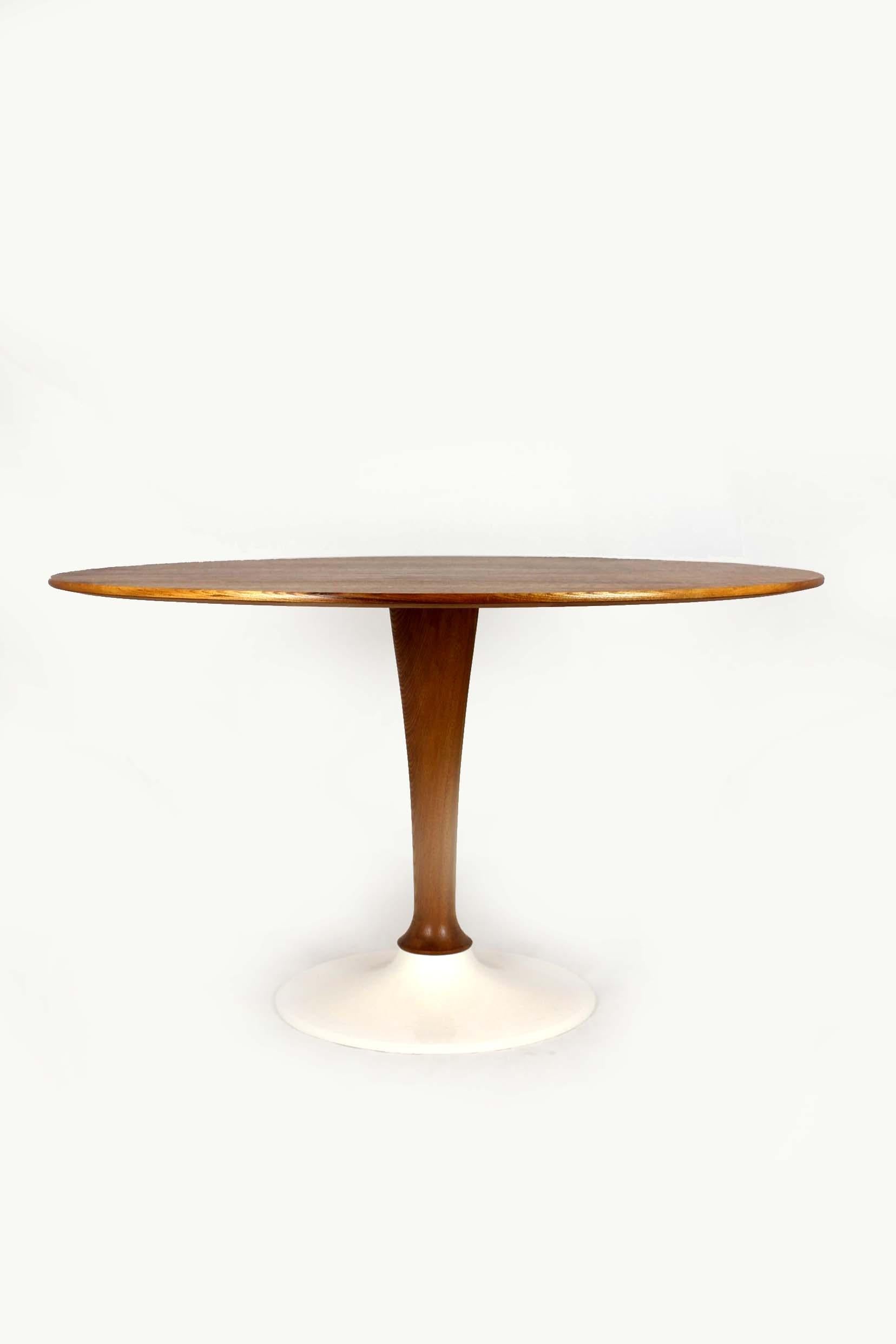 This elegant mid-century modern dining table was produced by Drevotvar in the former Czechoslovakia during the 1960s–70s. It features a beautifully grained walnut veneer top, resting on a sculptural turned wooden column and a heavy, white-painted
