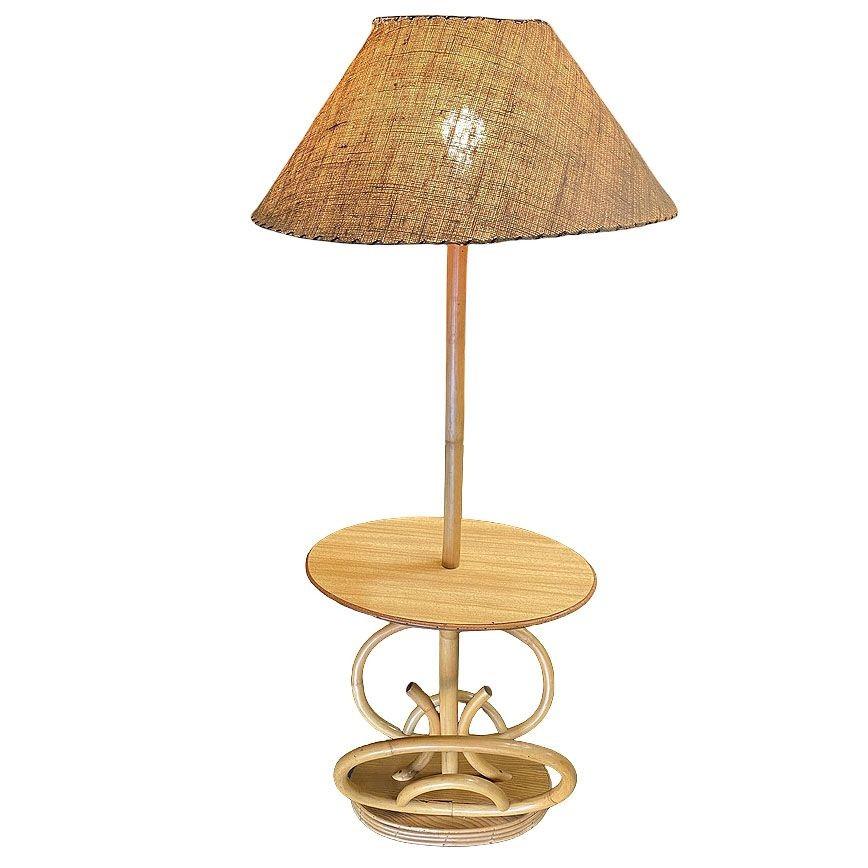 This beautifully restored rattan pole lamp features a decorative single rattan pole centered around a Formica drink side table fixed to a mahogany and rattan oval base, acting as a magazine holder. This lamp is perfect for a mid-century lounge or