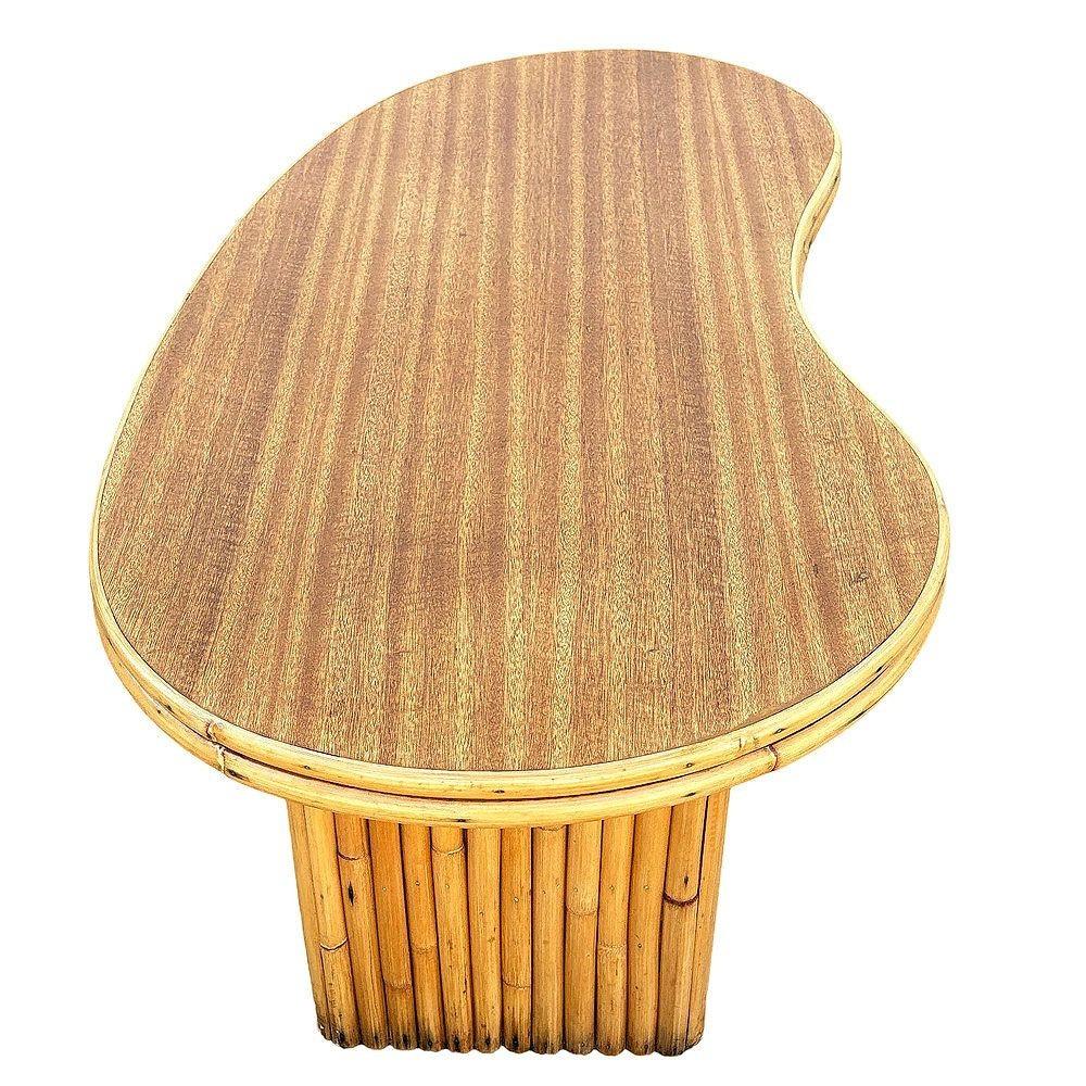 This beautifully restored rattan and Formica coffee table boasts a bold amoeba-shaped top, embodying playful mid-century blending tropical style and vintage charm with modern comfort. The sleek, durable Formica surface contrasts beautifully with the