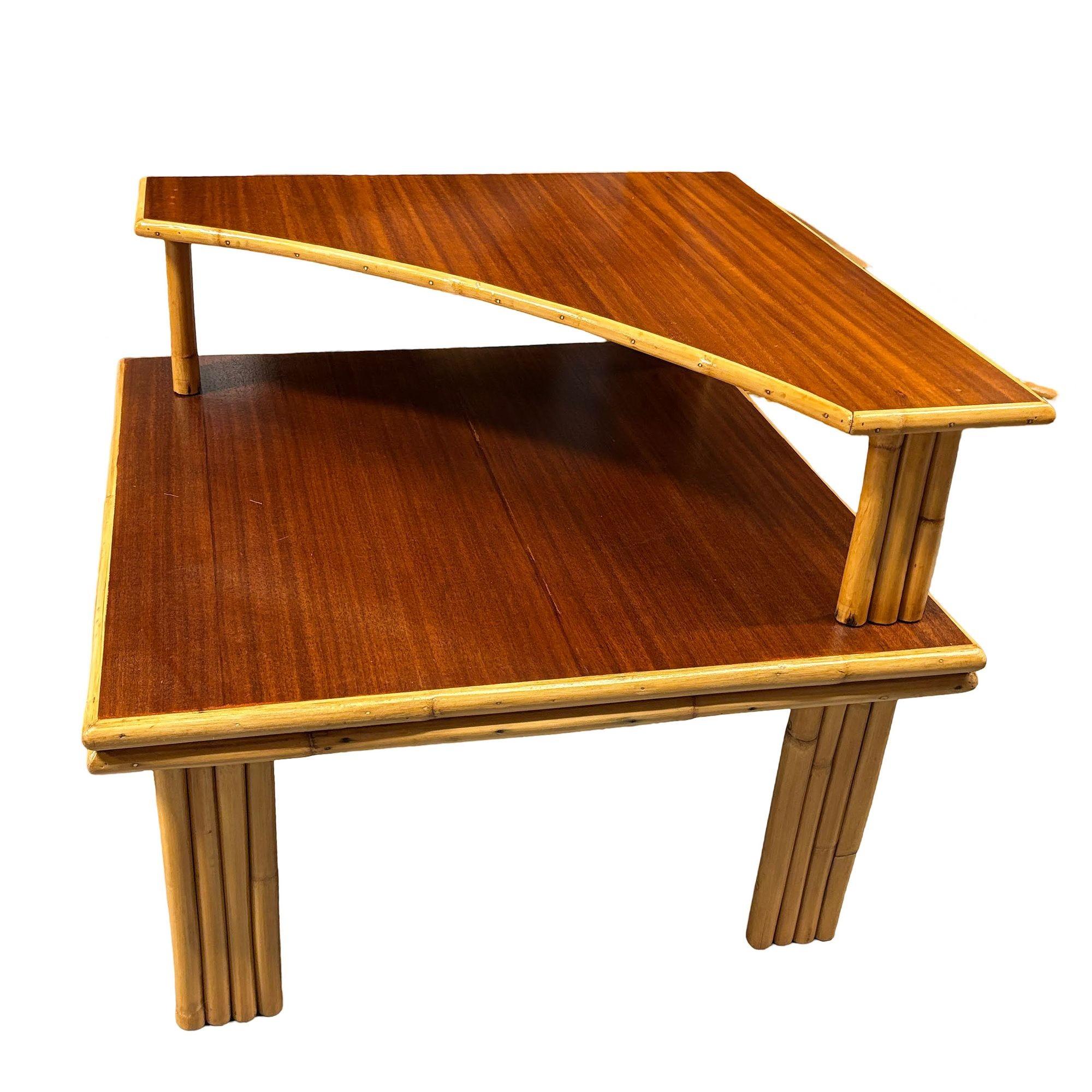 Esta mesa auxiliar esquinera de dos niveles, bellamente restaurada, con patas apiladas verticalmente y tablero de caoba teñida de oscuro. La mesa combina el encanto vintage con la comodidad moderna y ofrece versatilidad como pieza de esquina o