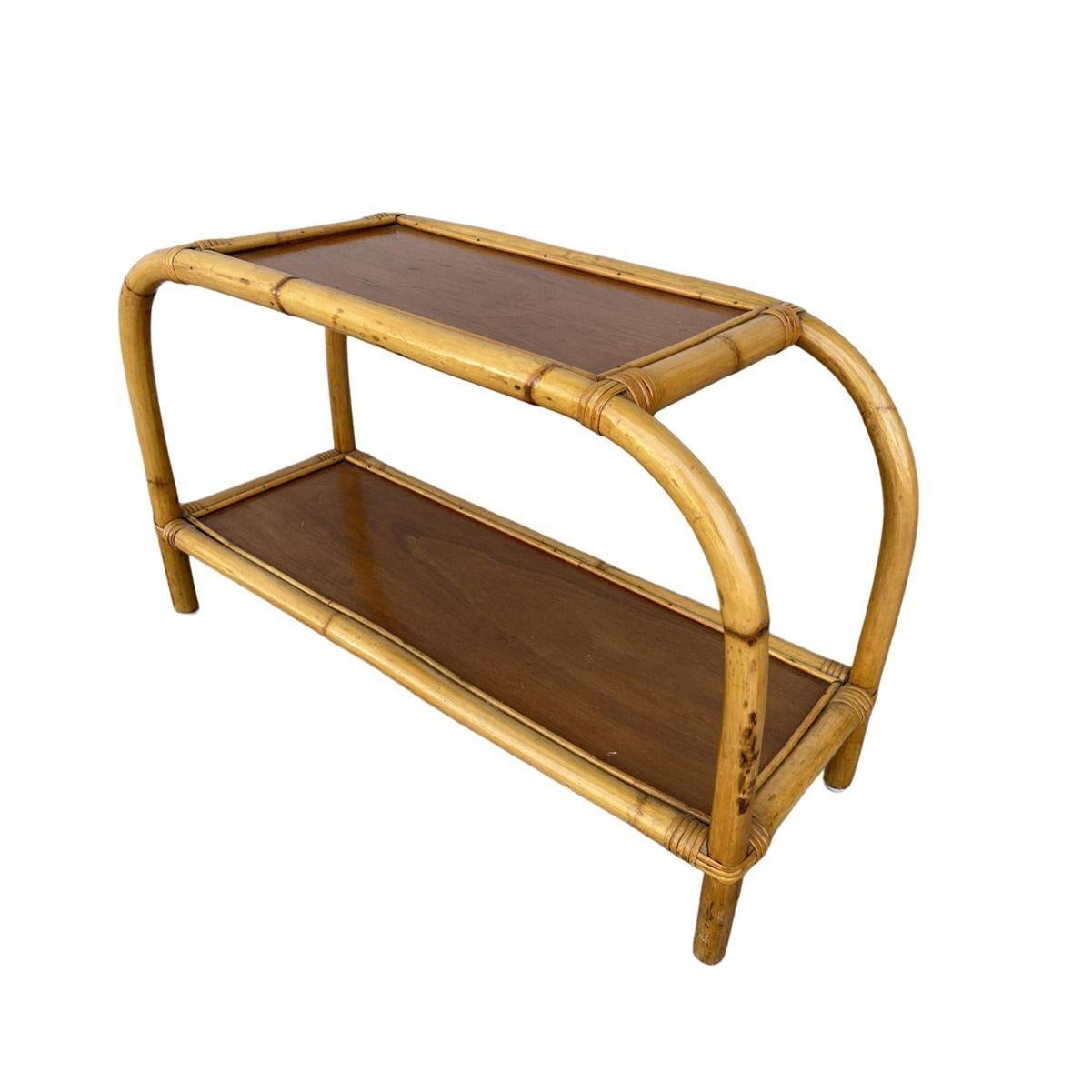 Cette table d'appoint en rotin à deux niveaux, inspirée par Paul Frankl et datant du milieu du siècle dernier, est dotée de plateaux en acajou, d'accents enveloppés d'osier et de pieds arqués et pliés uniques. Cette table de style Franl est
