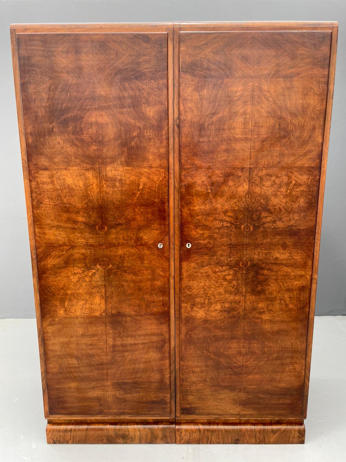 This elegant two-door wardrobe was produced in former Czechoslovakia as part of a broader national furniture production program that carried strong influences of Art Deco design. Made between the 1930s and 1960s, it features a symmetrical walnut