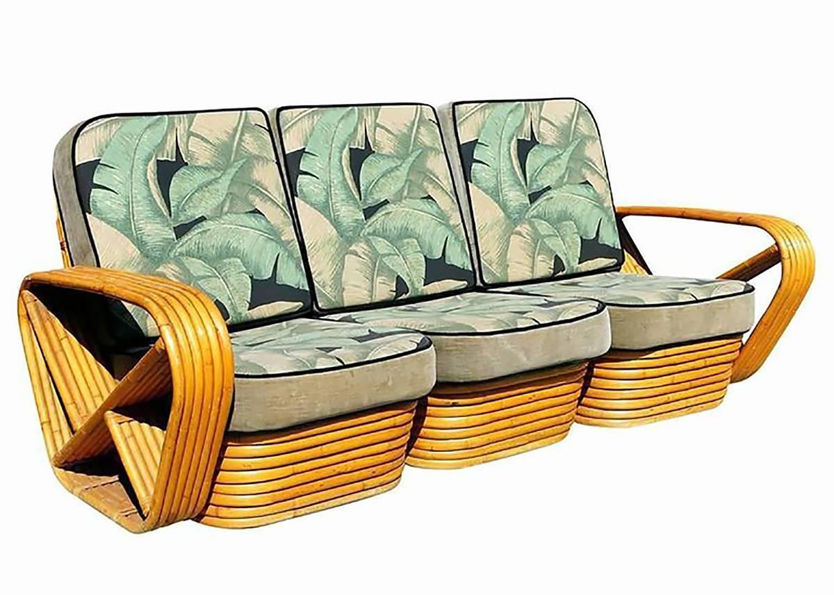 Paul Frankl style rattan living room set including a matching three-seat sectional sofa, lounge chair, ottoman, coffee table and pair of end tables. Both the sofa and chair feature the famous six strand square pretzel side arms and stacked rattan