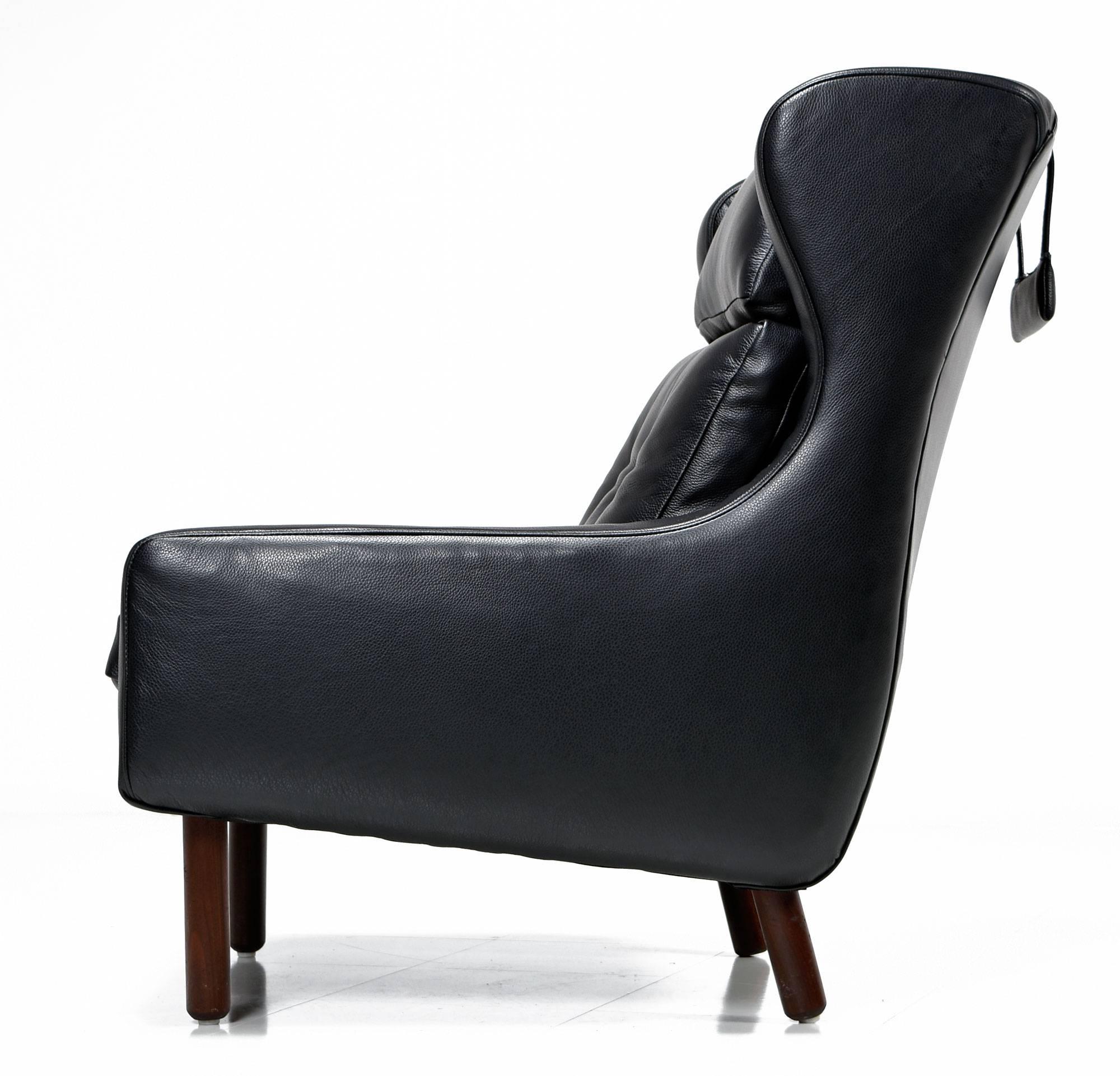 Fully restored with new luxurious black leather. This Mid-Century Modern lounge chair had no marking, but it's clearly in the style of Frits Henningsen and Svend Skipper, made in the 1960s. This wingback armchair features a weighted neck pillow in