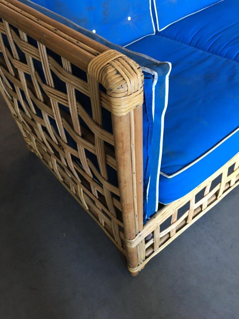 Mid Century Baughman style rattan sofa with a pole rattan frame and stick rattan sides. The seats are covered in tuft blue cloth cushions.

Measures:
Sofa: 34