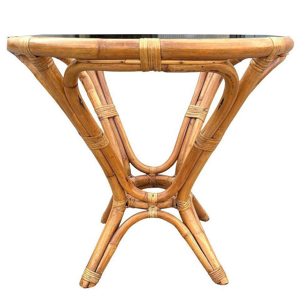 This beautifully restored round Frankl-inspired rattan side table features a sculptural hourglass rattan base with a round glass top. The table combines tropical style and Mid-century design. The table is meticulously refinished to highlight the