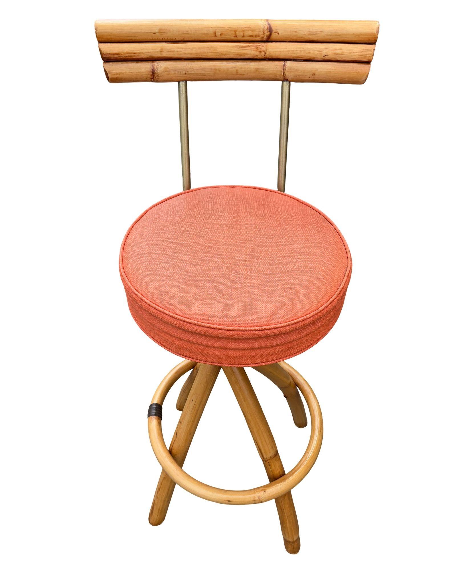 Dieses stilvolle Paar restaurierter Rattan-Barhocker verfügt über gedrehte Beine, runde Fußstützen und leuchtend orangefarbene Kissen. Ein Hocker verfügt über eine Rückenlehne aus Rattan mit Lattenrost und Messingstützen für zusätzlichen Komfort.
