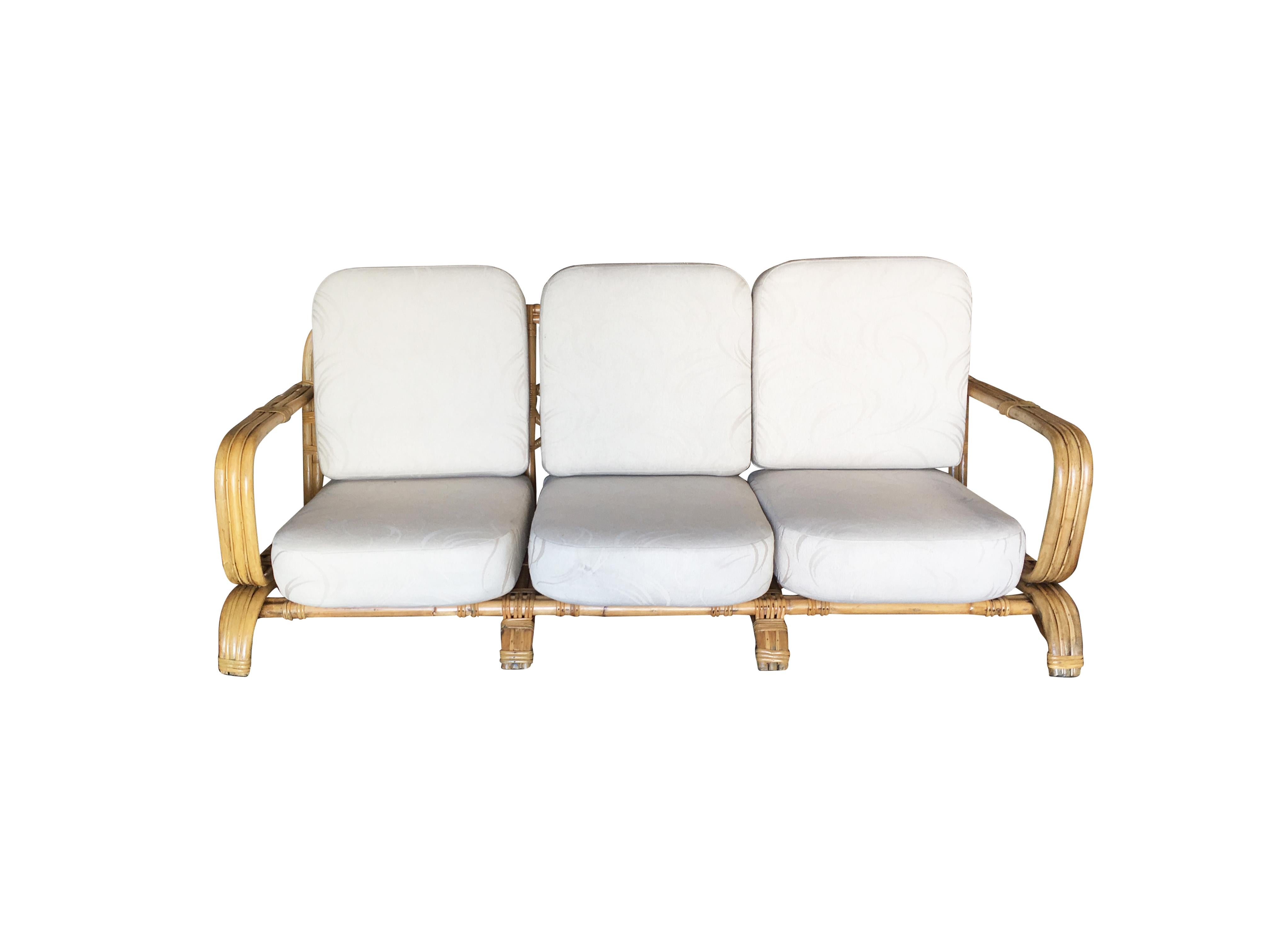 Restored Paul Frankl original wrap around 3-seat sofa with triple pole rattan design. This unique sofa features a bent pole design which wraps around the bottom and top forming the arm of the chair. This sofa rests on four arched arms forming a