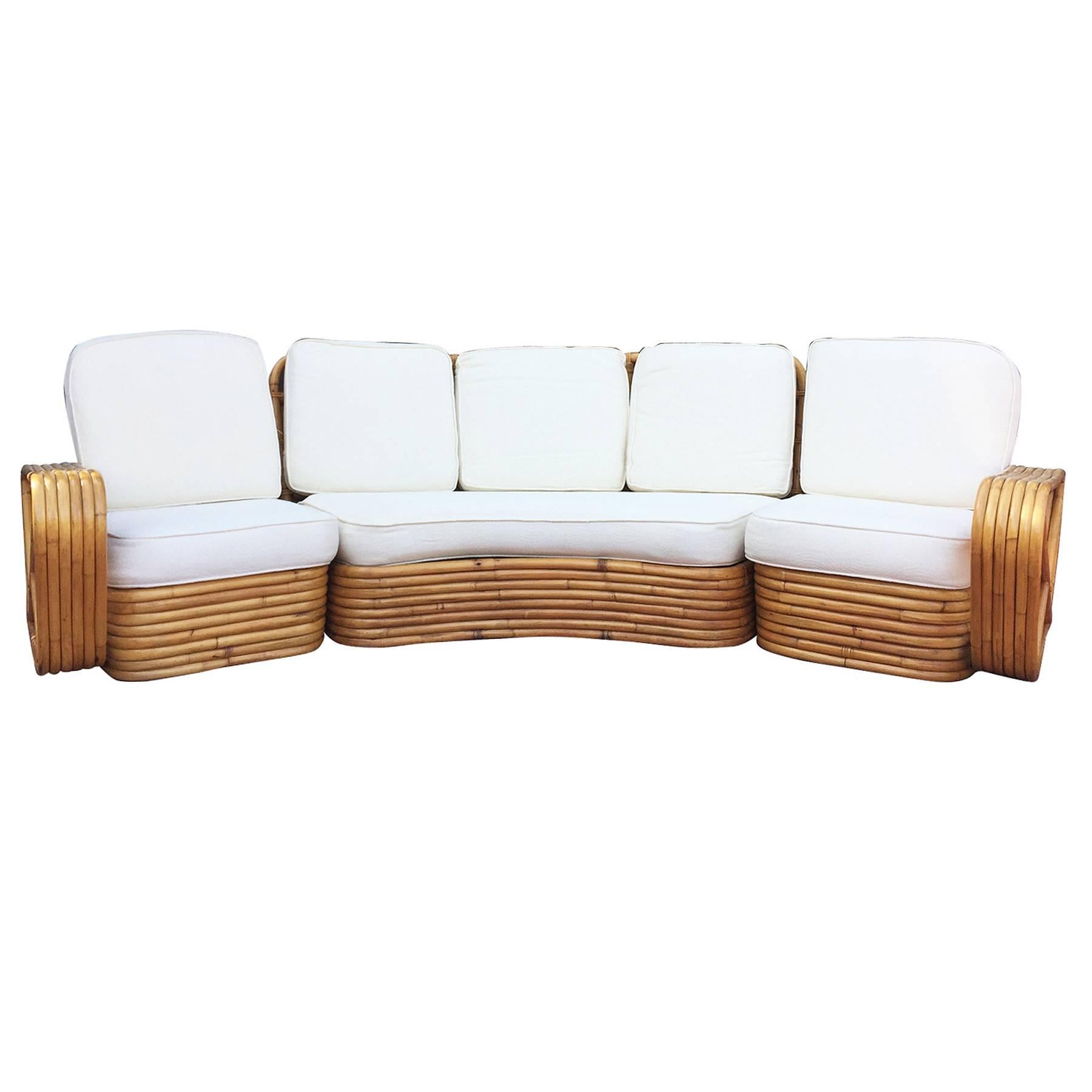 Six strand square pretzel curved rattan sectional sofa designed in the style of Paul Frankl. This sofa features a stacked rattan base with six strand square pretzel arms and is divided into a three sectionals, two end pieces that each fit one person