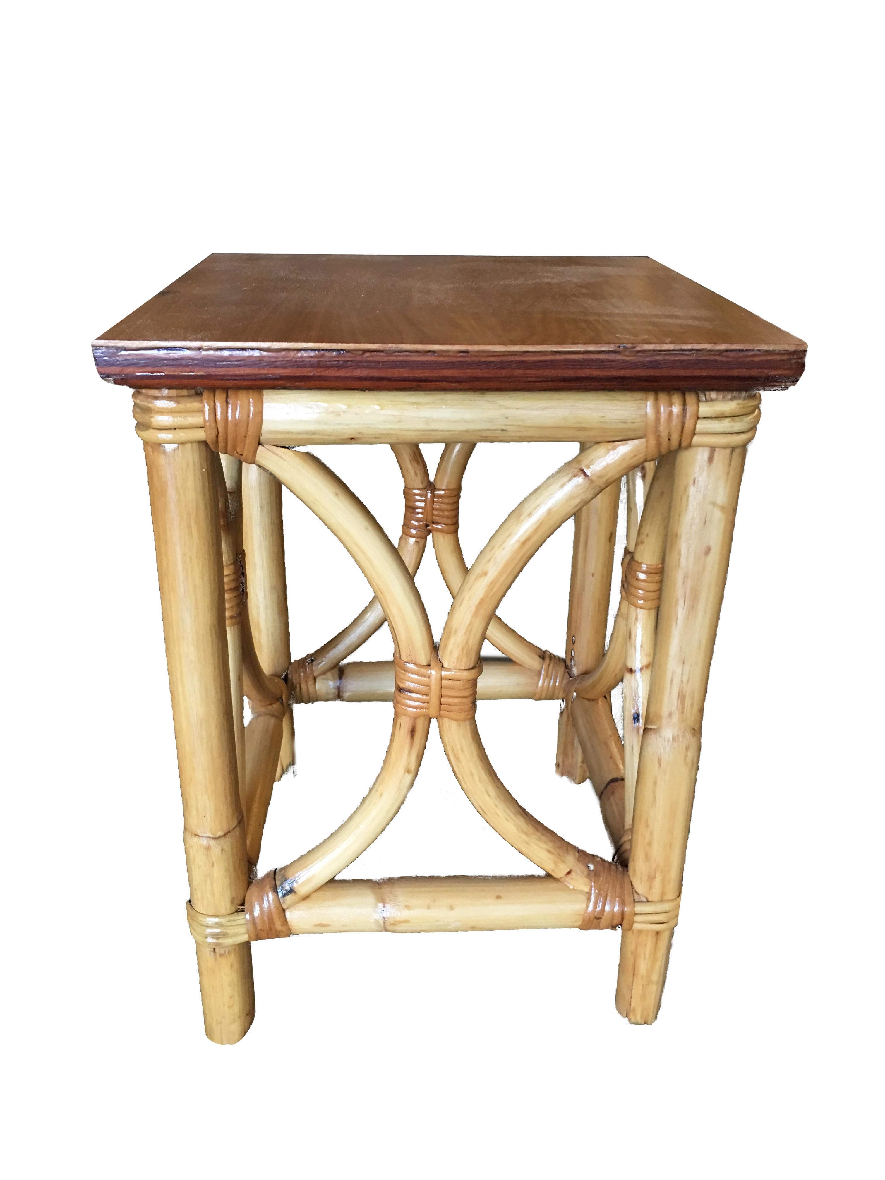 This mid-century rattan square side table boasts a mahogany tabletop held by twin arch side rattan poles, evoking the style of Paul Frankl. Professionally restored in 2019, it combines timeless design with meticulous craftsmanship, offering a