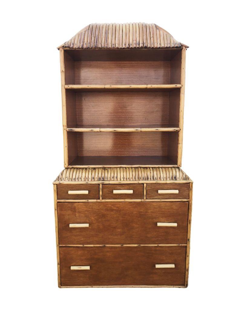 Questa libreria/ripostiglio in rattan Art of Vintage su misura, splendidamente restaurata, unisce lo stile al fascino vintage e al comfort moderno con una serie di 5 cassetti lungo la parte inferiore e uno scaffale incorporato che adorna la parte