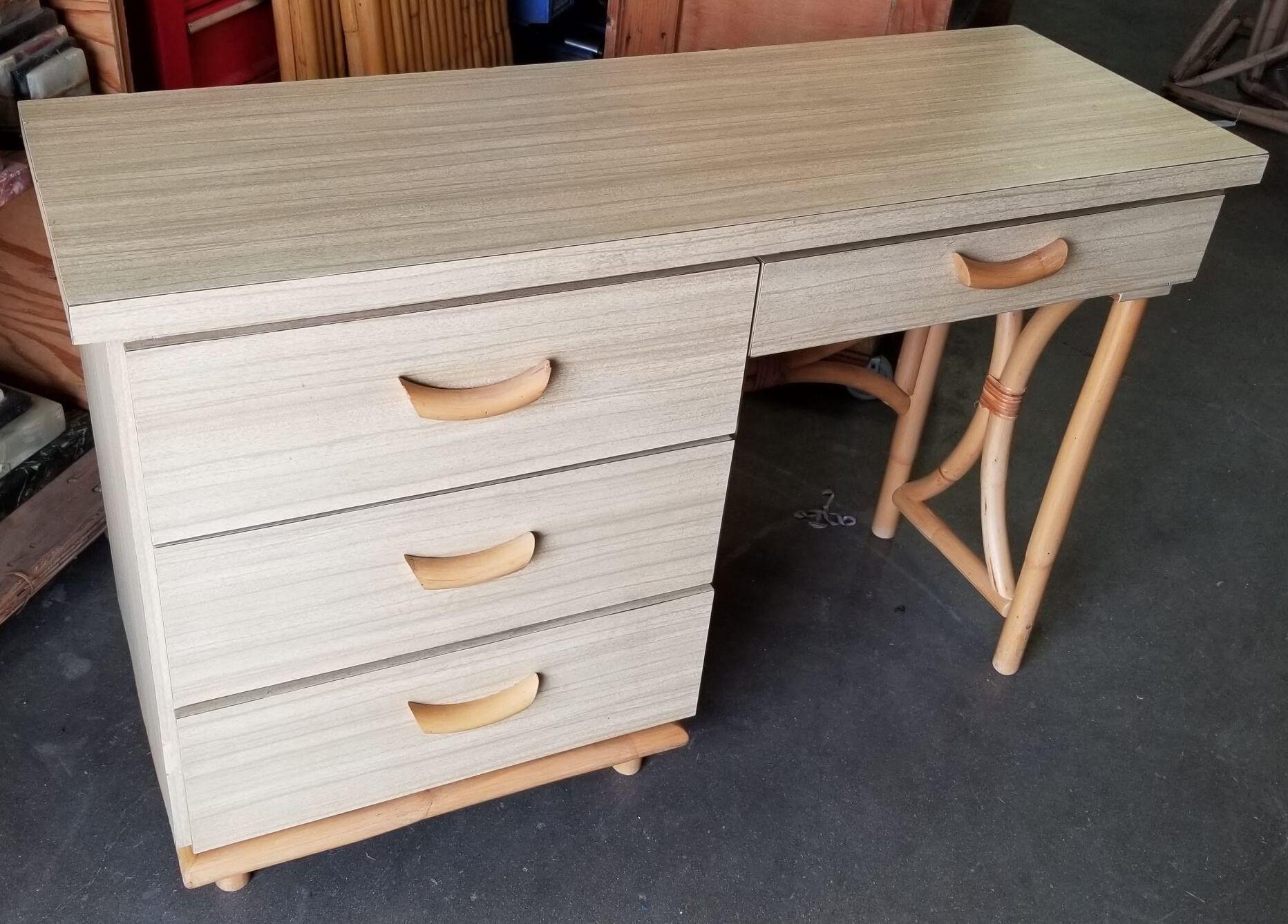 This restored mid-century desk showcases blonde Formica with drawers, enclosed in an hourglass-shaped rattan frame. It's unique design flaunts curved rattan drawer pulls, exuding a tropical vibe. With its blend of rattan and Formica, this piece
