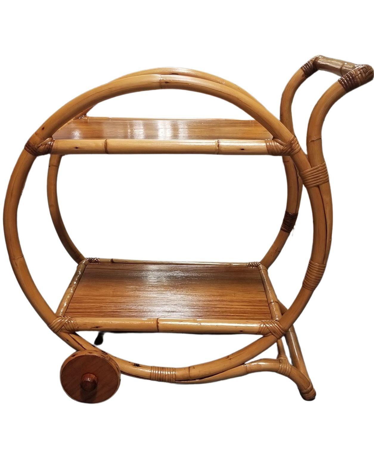 Restored single-strand rattan bar cart or tea cart with a top handle and front wheels. The bar cart features a large circular that loops the entire circumference of the bar cart. The cart fits in perfectly with the Paul Frankl based mid-century