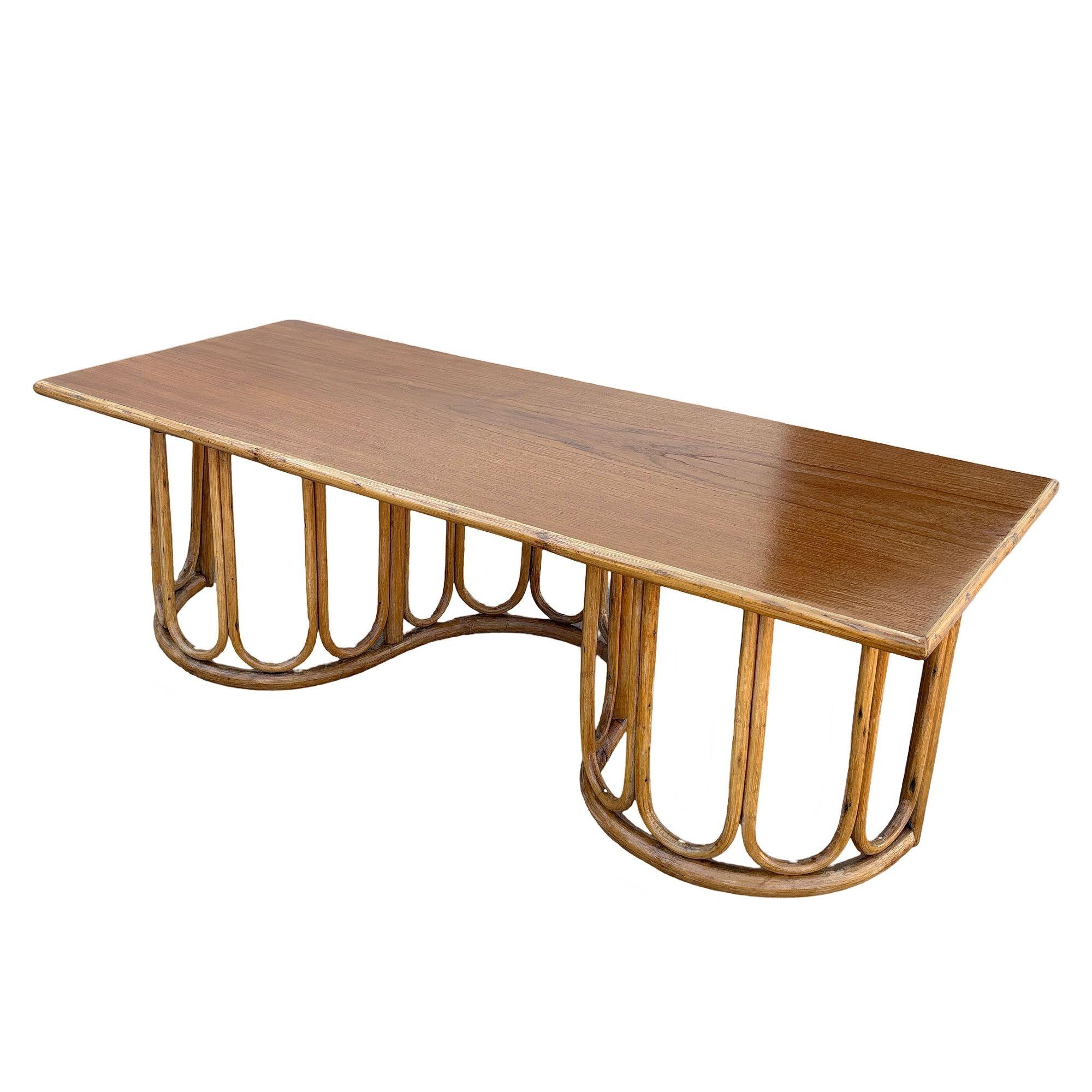 This beautifully restored Paul Frankl-inspired rattan blends vintage charm with modern comfort. This restored rattan and mahogany coffee table features a captivating wavy base, adding fluidity and movement to its design. The warm mahogany top