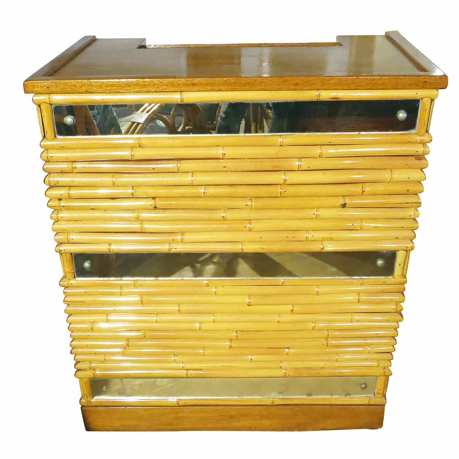 Unique, circa 1940 rattan bar made with a pole rattan front accented by cut-out mirror sections and solid Mahogany trim. Drinks are easily served from the two-tier solid mahogany top which easily keeps spirit bottles and drinking glasses separate.
