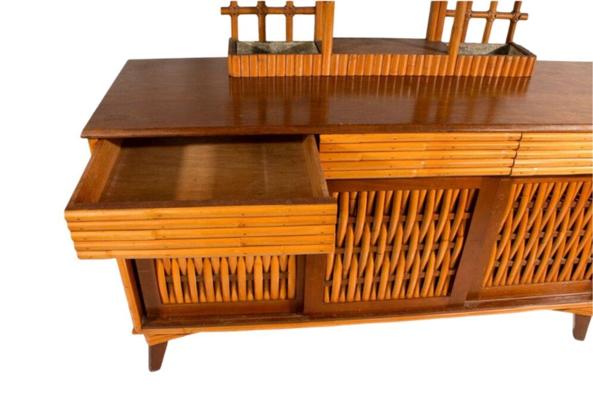 Upgrade your entertainment space with the Restored Rattan Credenza Media Console. Its distinctive design features woven front doors that add a touch of sophistication. Meticulously restored, this piece seamlessly blends vintage charm with modern